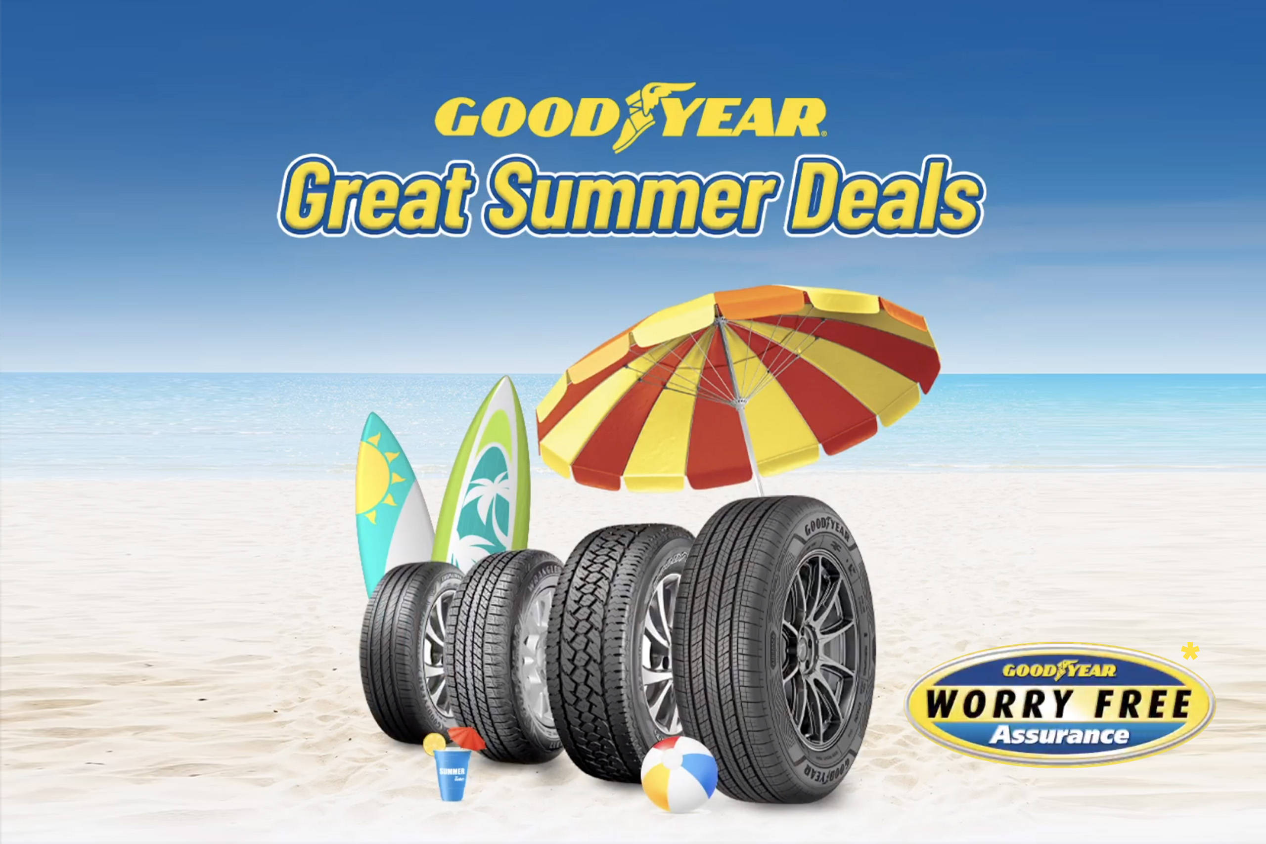 advertising 桌布 壁紙 — Goodyear 輪胎排列在陽光明媚的海灘上，配有衝浪板、沙灘傘和夏季玩具，在清澈的藍天下。