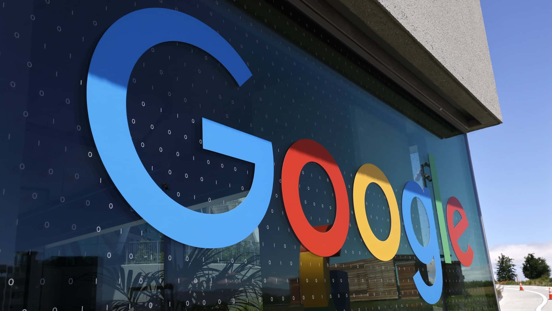 玻璃建築上的Google標誌，帶有二進制代碼圖案和天空倒影。 — Google 壁紙
