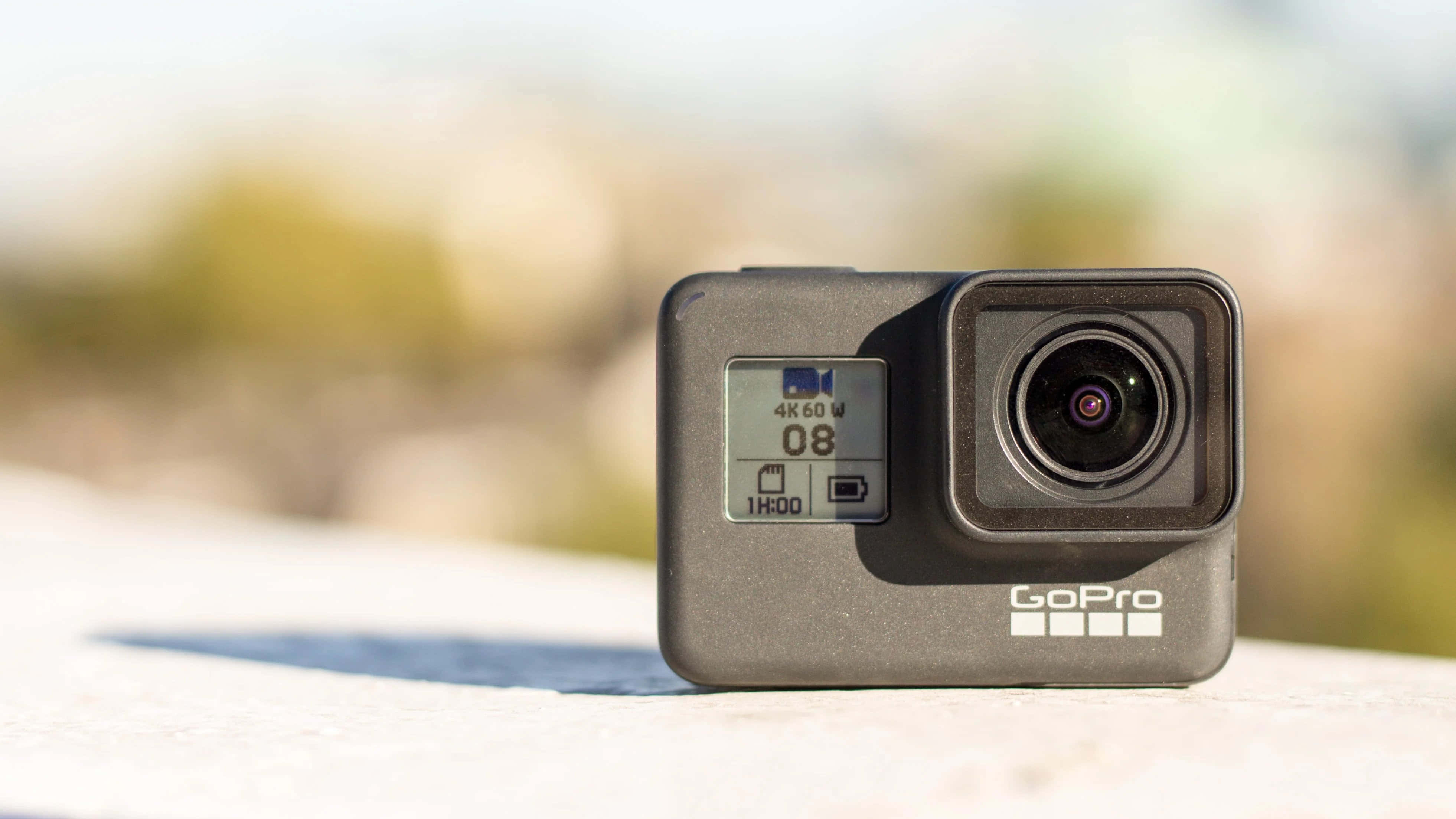 gopro 桌布 壁紙 — GoPro 運動攝影機放置在陽光照射的表面上，背景模糊自然。