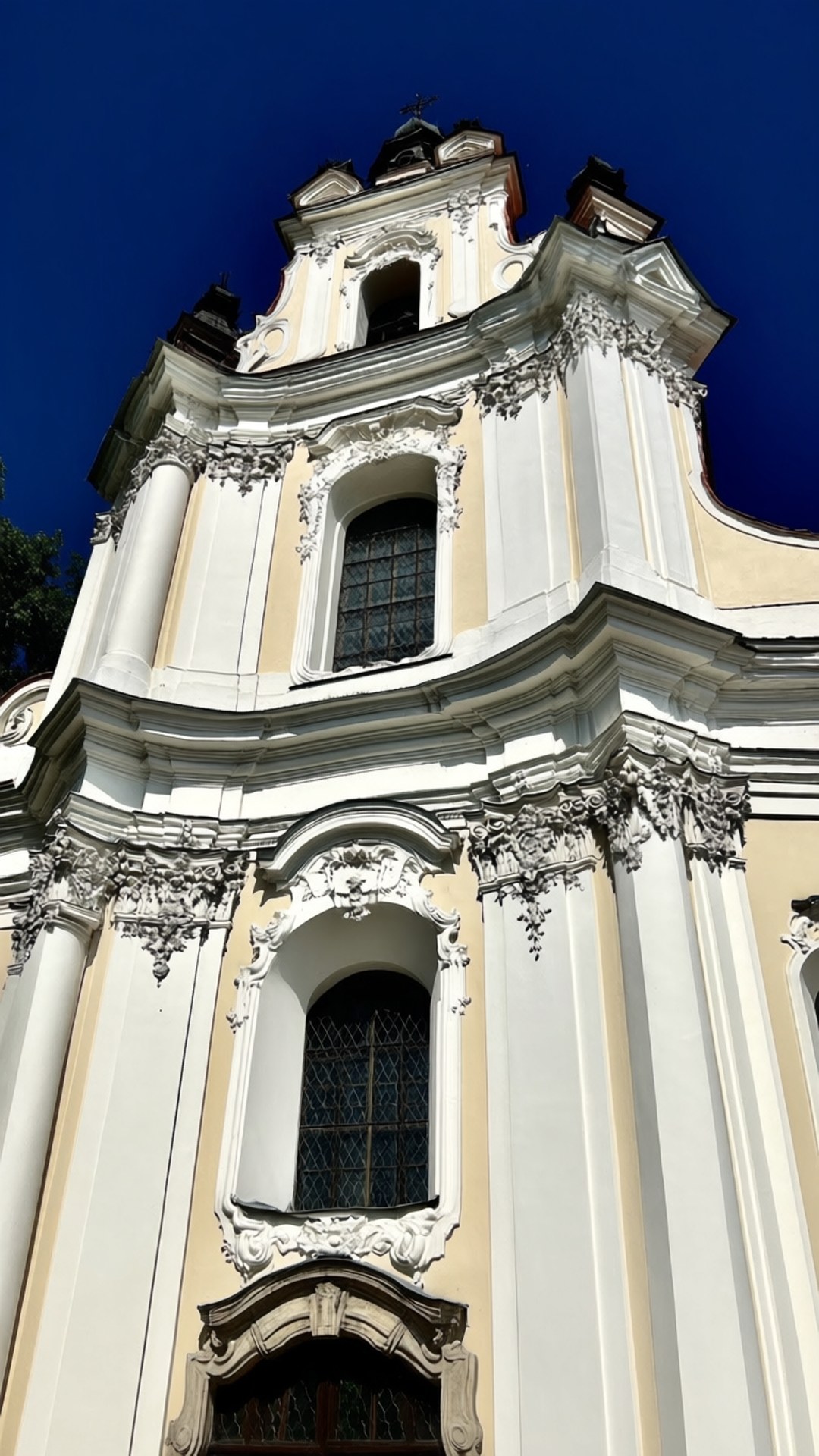 Baroque Facade Detail 壁紙 — 一座宏偉的巴洛克式教堂外牆，飾有華麗的白色石雕和深色窗戶，矗立在深藍色的天空下。