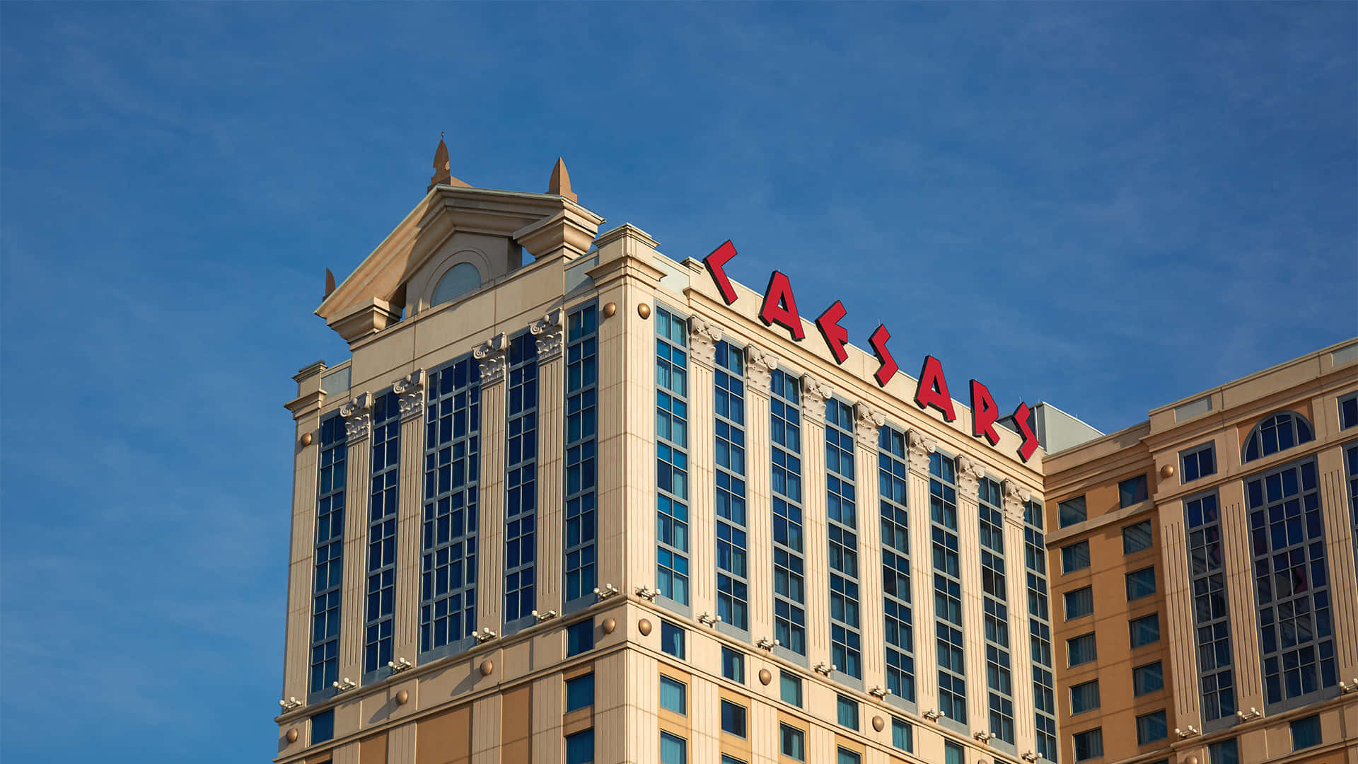 飯店 桌布 壁紙 — Grand Caesar's Palace 酒店塔樓在清澈藍天下，配有醒目的紅色標誌和反光玻璃窗。