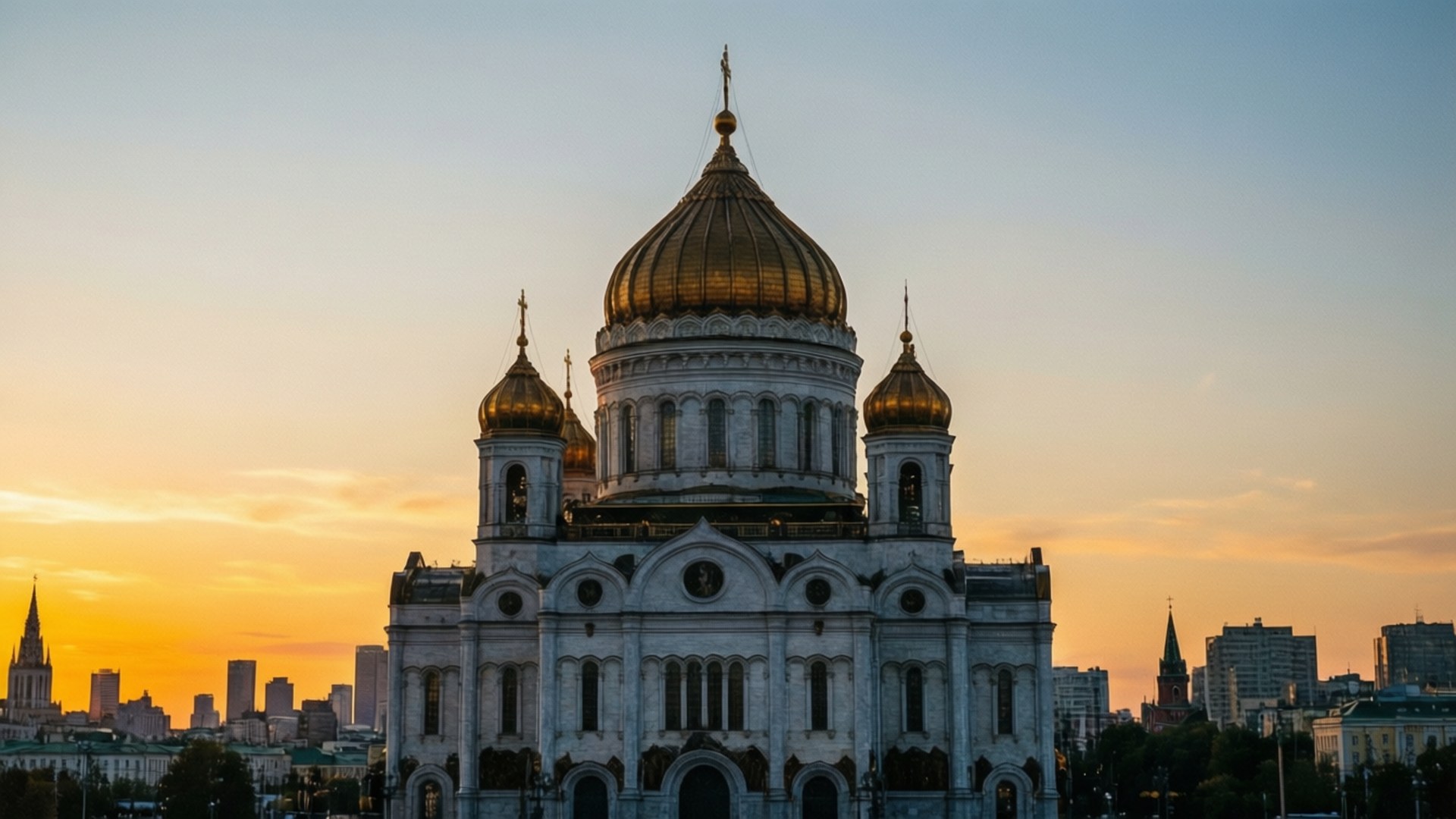 Moscow 桌布 壁紙 — 宏偉的大教堂，金色圓頂在溫暖的日落天空下，映照著城市天際線。
