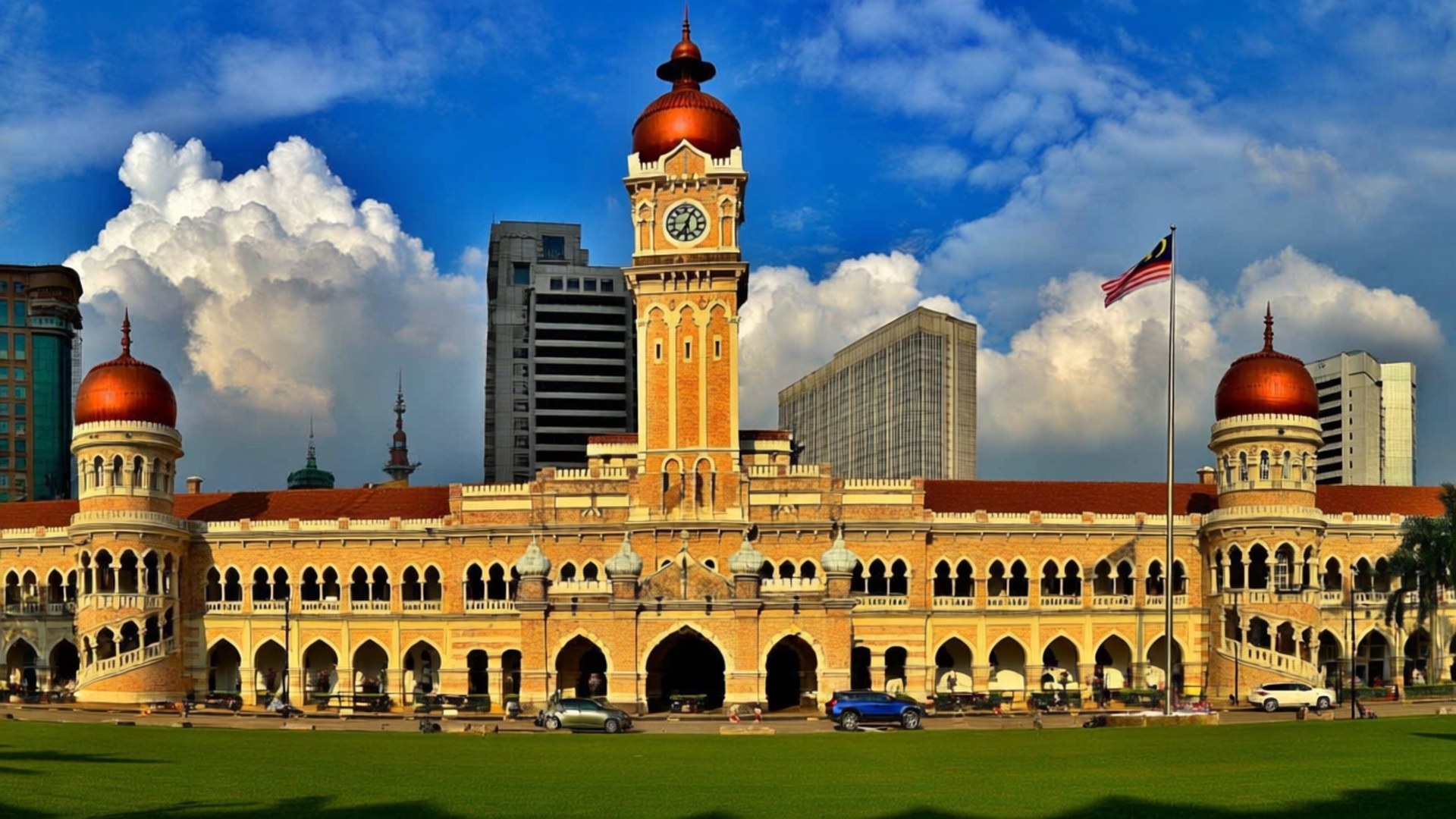 Sultan Abdul Samad 壁紙 — 大型殖民時期鐘樓建築，擁有紅色圓頂和拱形柱廊，矗立在蔚藍的天空下，白雲朵朵。
