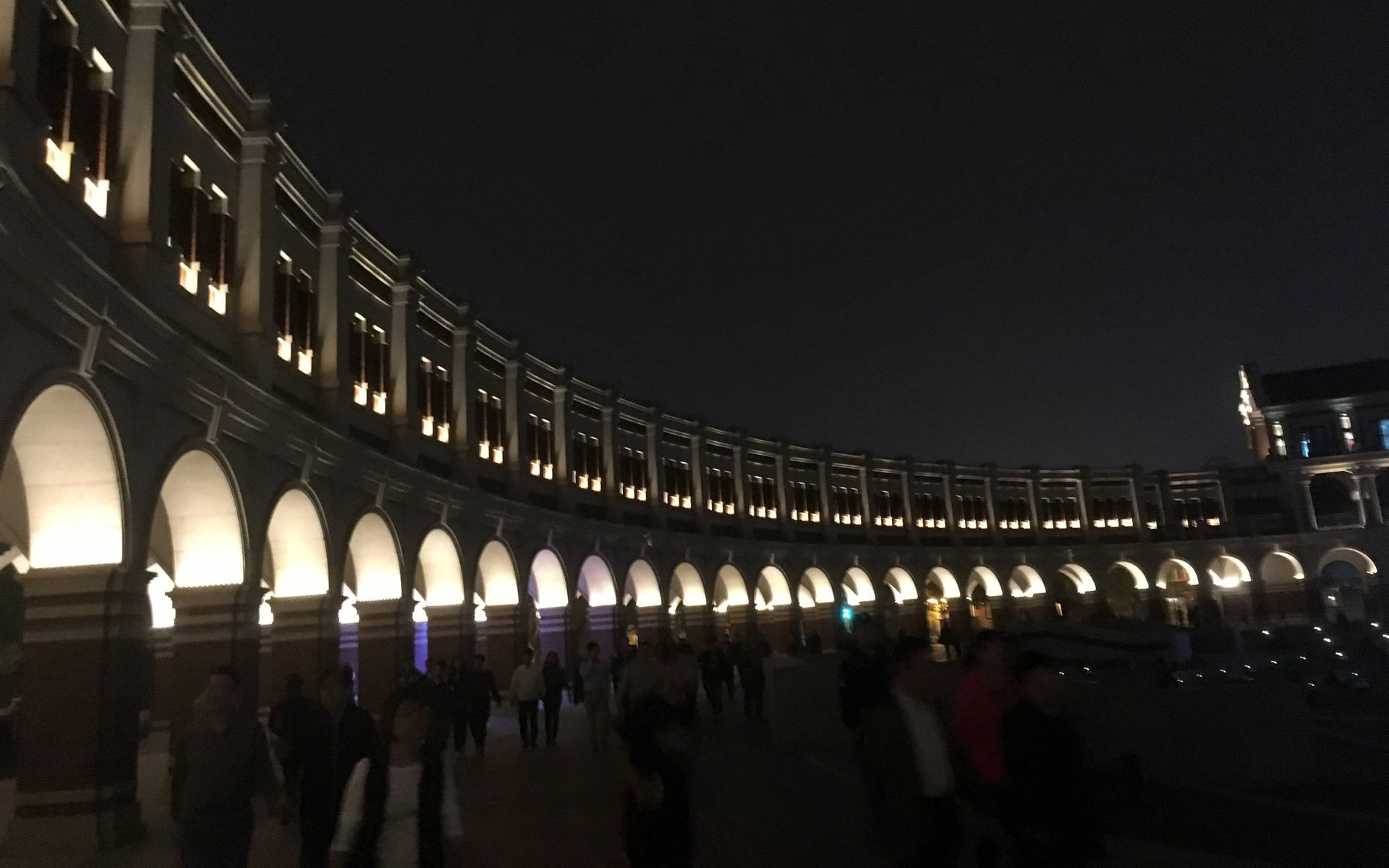夜晚燈光下的石拱門廣場景觀，有人漫步。 — 台北 壁紙