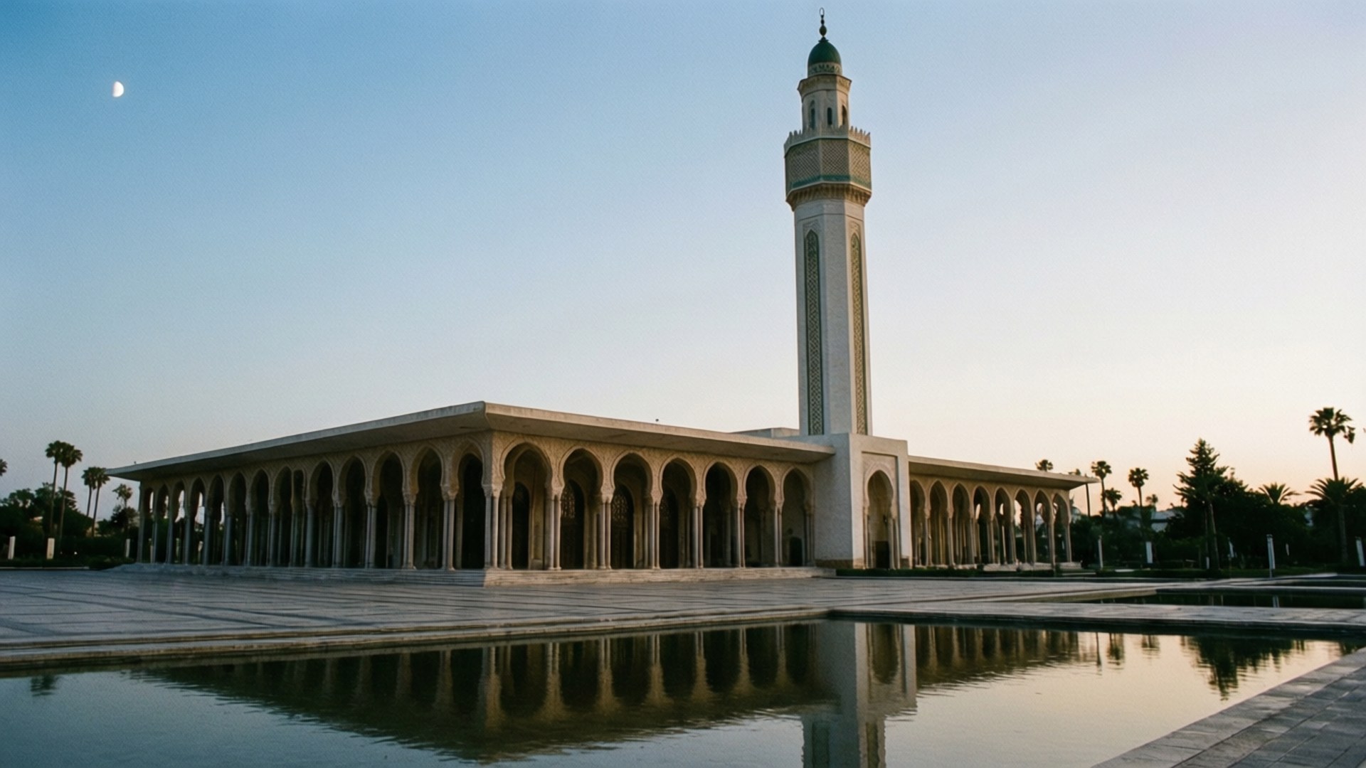 Grand Mosque Algiers 壁紙 — 一座宏偉的清真寺，擁有高聳的宣禮塔和拱形柱廊，在暮色天空下新月映照的寧靜水池中倒映。