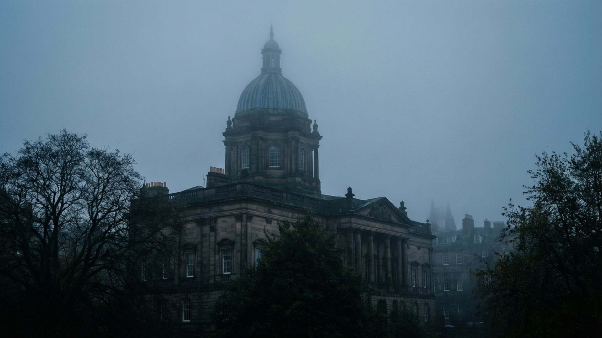 The University Of Edinburgh 桌布 壁紙 — 一座宏偉的新古典主義建築，帶有圓頂屋頂，從濃霧中浮現，在灰色天空下由光禿禿的樹木襯托。