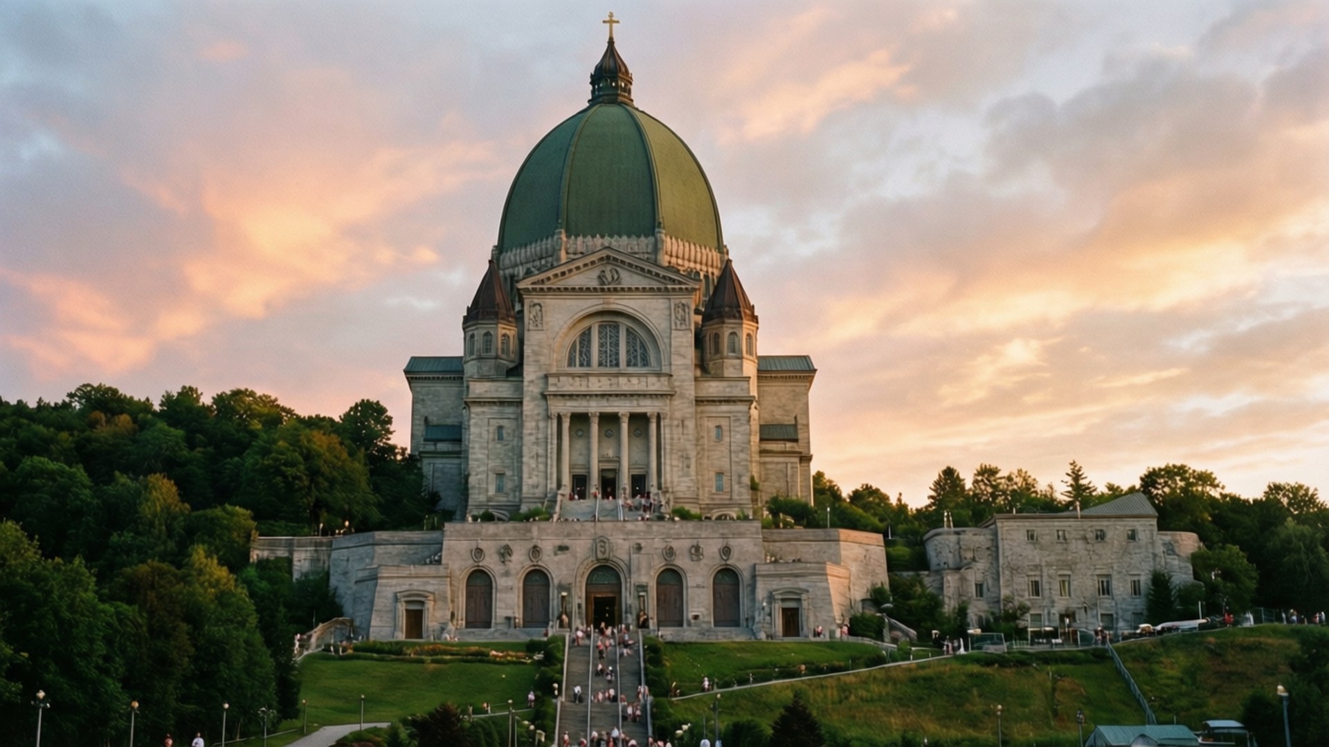 Saint Joseph's Oratory Majestic 壁紙 — 一座宏偉的石造大教堂，帶有綠色圓頂，在日落時分雄偉地矗立在山丘上，周圍環繞著茂密的樹木和寬闊樓梯上的遊客。