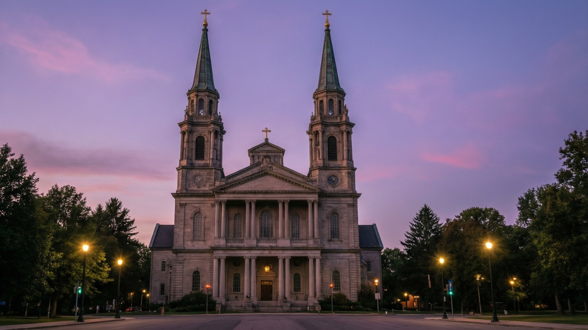 Basilica at Dusk 壁紙 — 一座宏偉的石造大教堂，擁有雙塔，在佈滿粉紅和紫色雲彩的暮色天空中熠熠生輝。