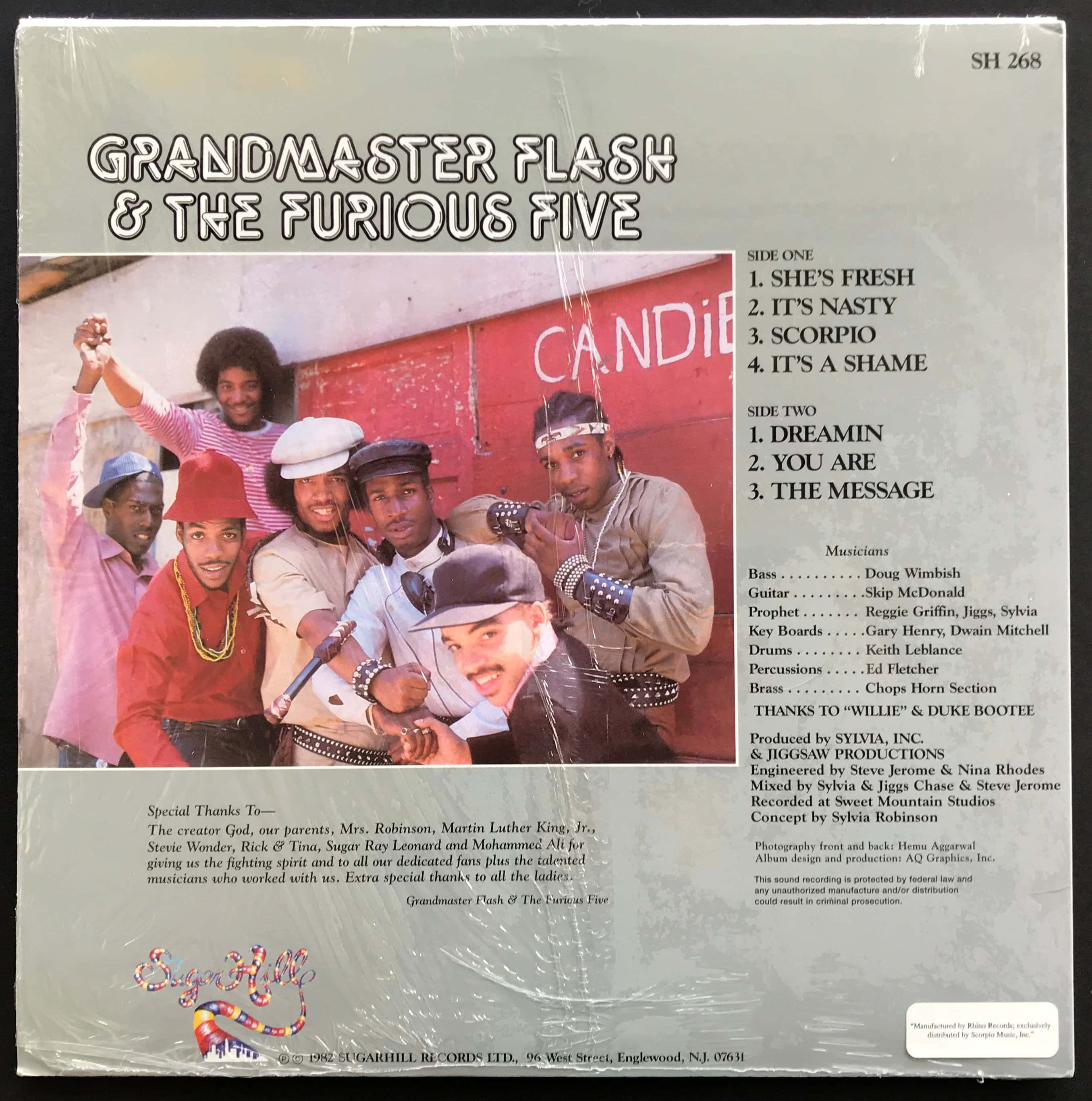 vintage 90s aesthetic 桌布 壁紙 — Grandmaster Flash 和 The Furious Five 在復古專輯封面上，於紅色糖果店牆前充滿活力地擺姿勢。