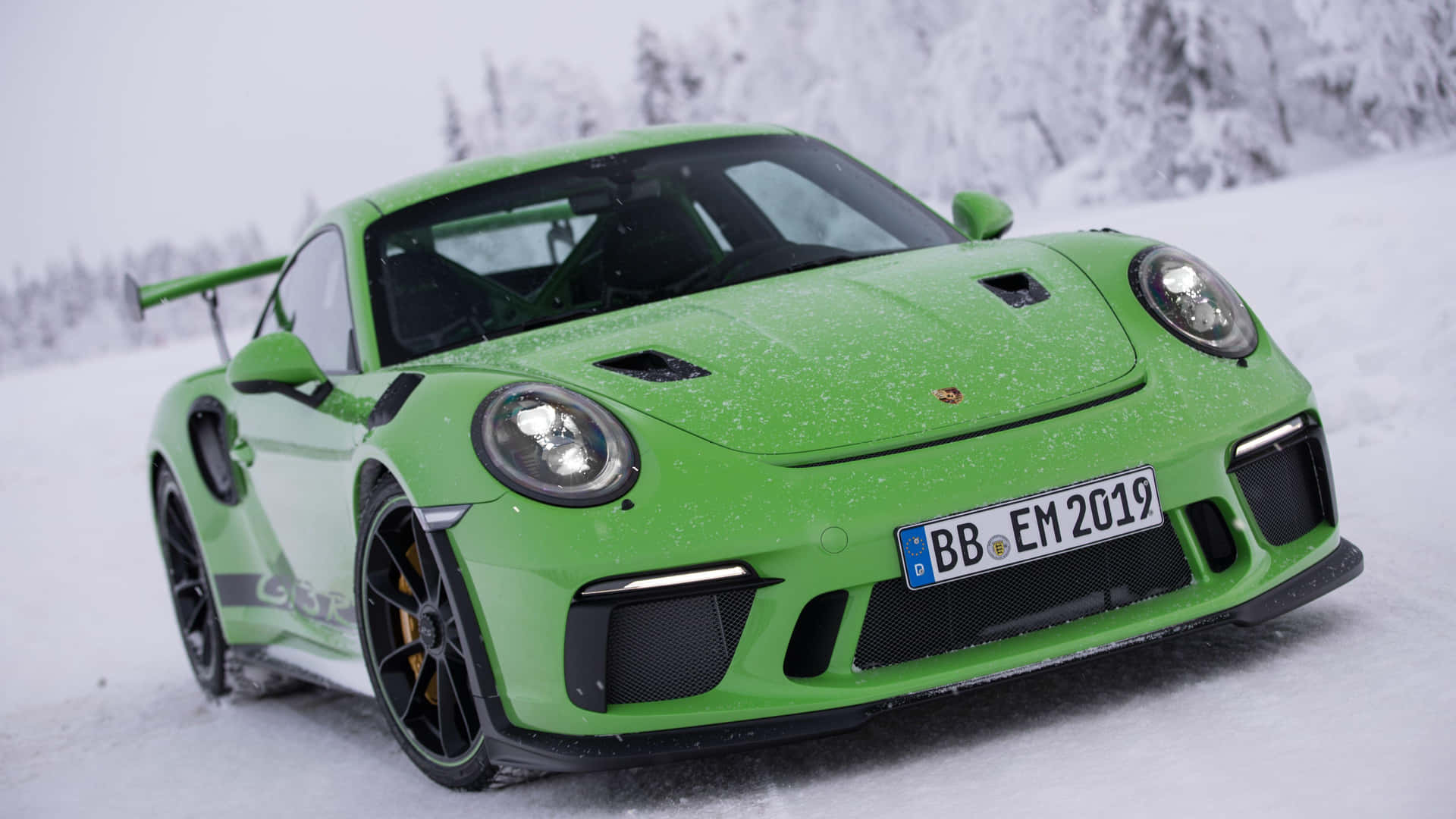  壁紙 — 一輛鮮綠色的保時捷911 GT3 RS在雪景中矗立，背景是覆蓋著雪的樹木。