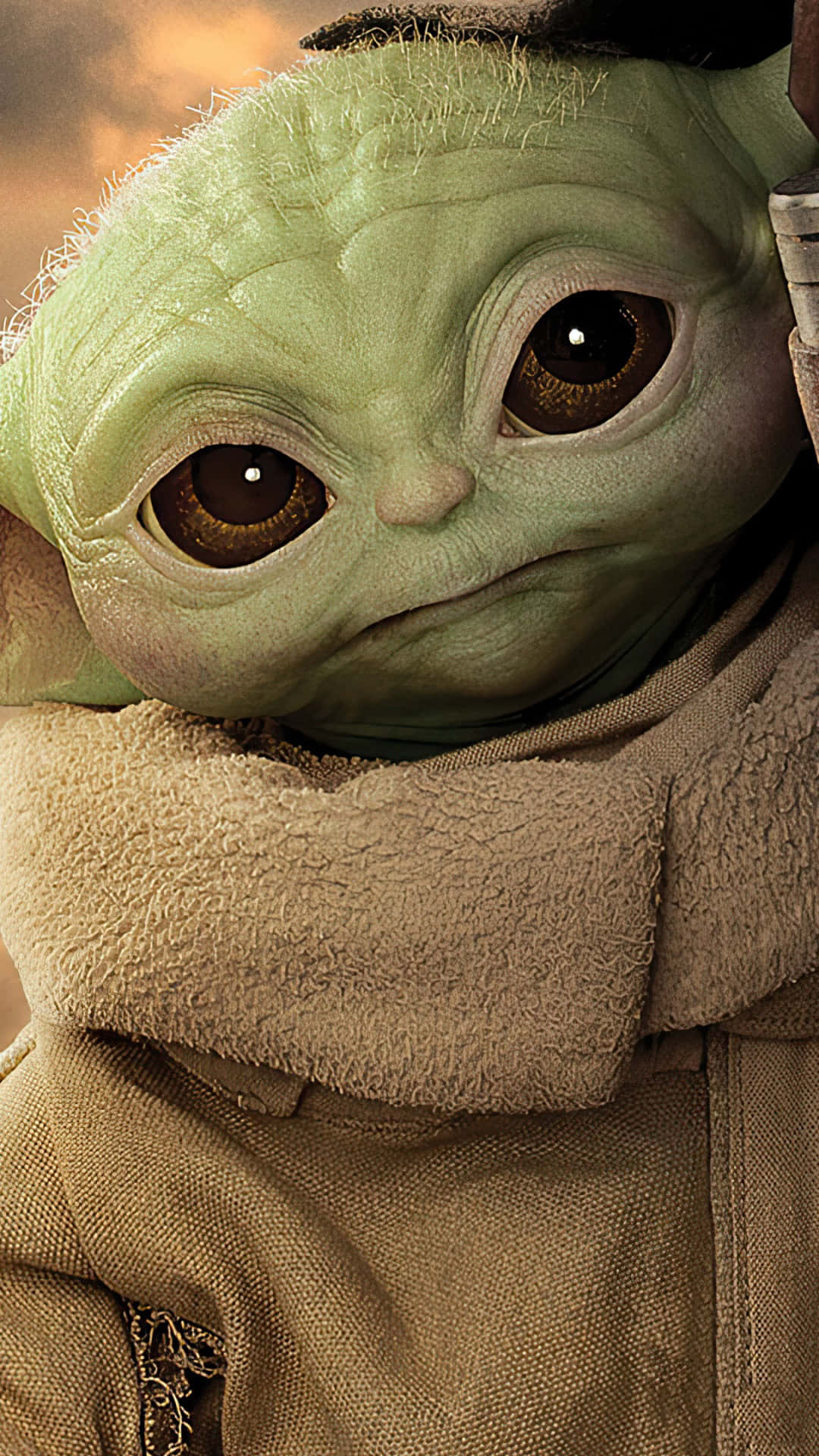 Baby Yoda Phone 桌布 壁紙 — Grogu 的大而有表現力的眼睛和皺紋綠色臉部特寫，包裹在米色連帽長袍中。