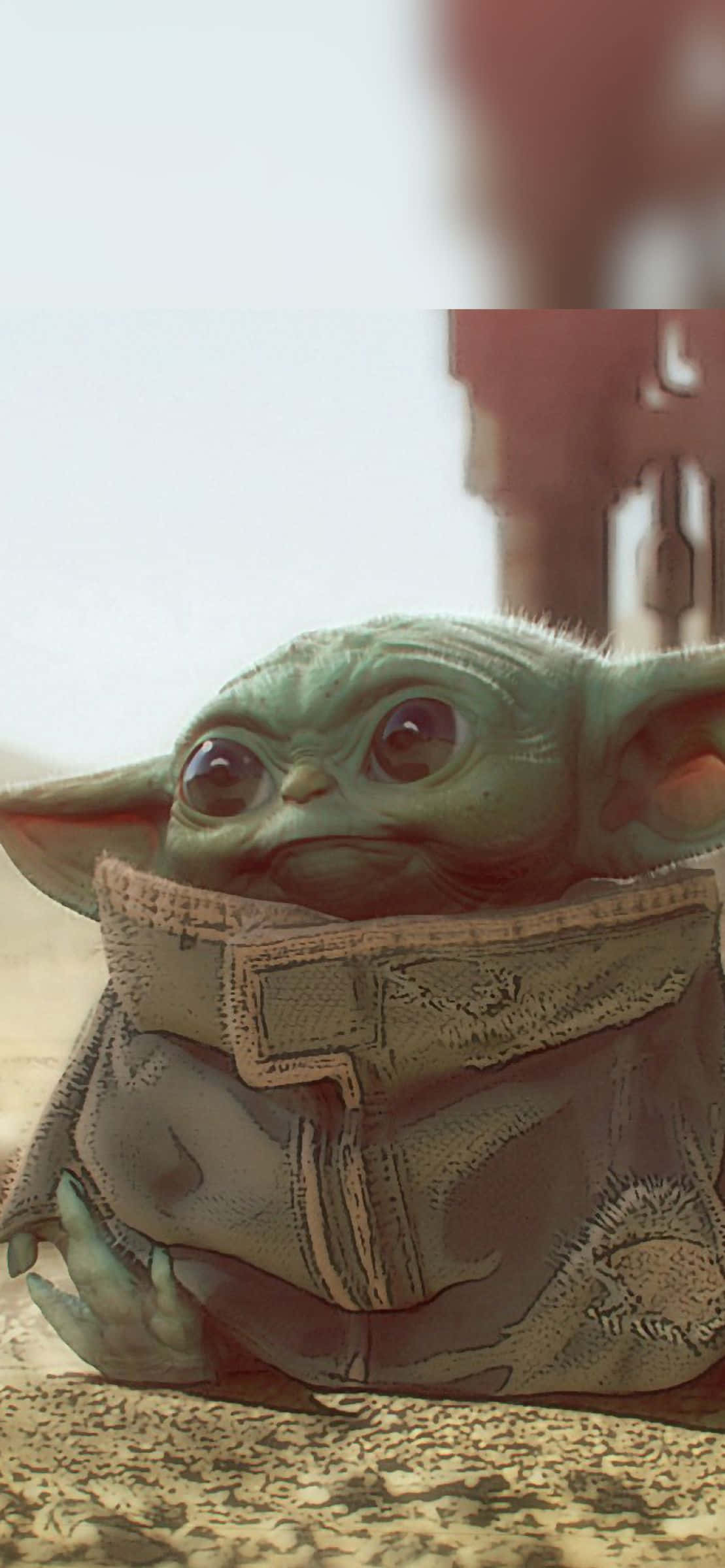 Baby Yoda iPhone 桌布 壁紙 — Grogu（綠色嬰兒尤達）的特寫，身穿破舊外套坐在岩石地面上，背景是模糊的沙漠。