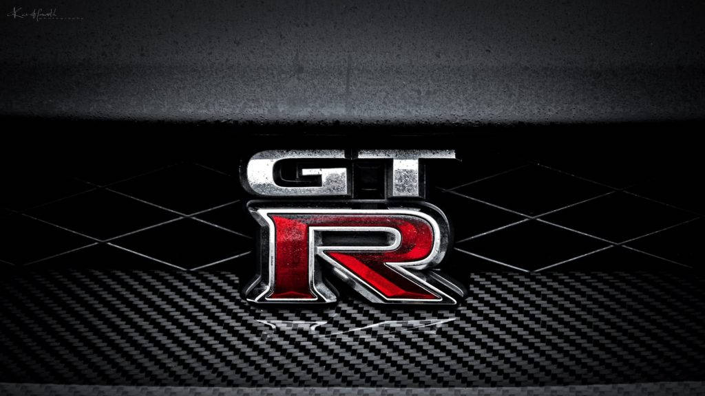 碳纖維表面上的 GTR 標誌，帶有金屬紅色和銀色飾面。 — 4K 壁紙
