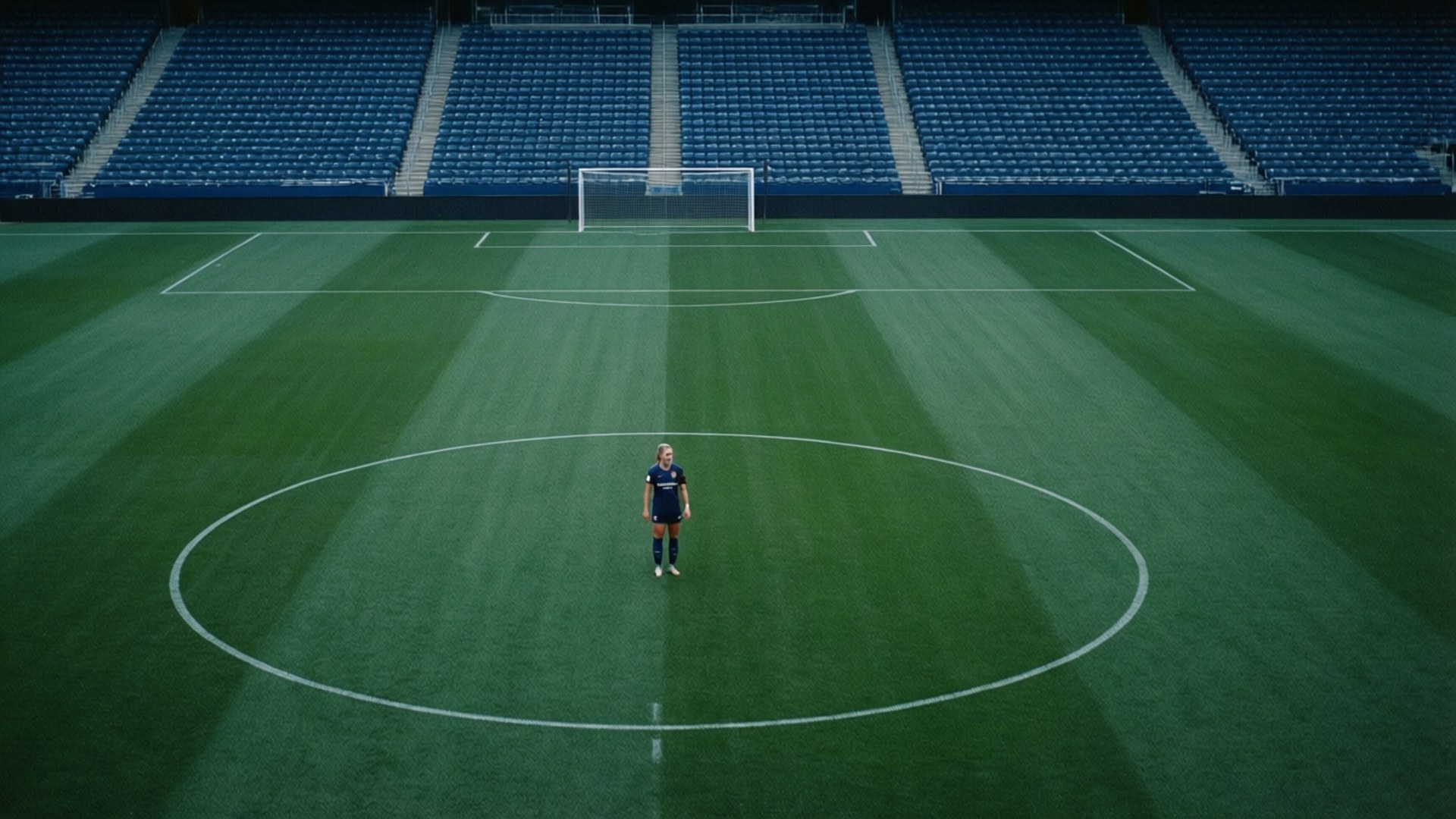 becky sauerbrunn 桌布 壁紙 — 一名孤獨的足球運動員站在空蕩蕩的球場中圈，在冰冷的人工燈光下。