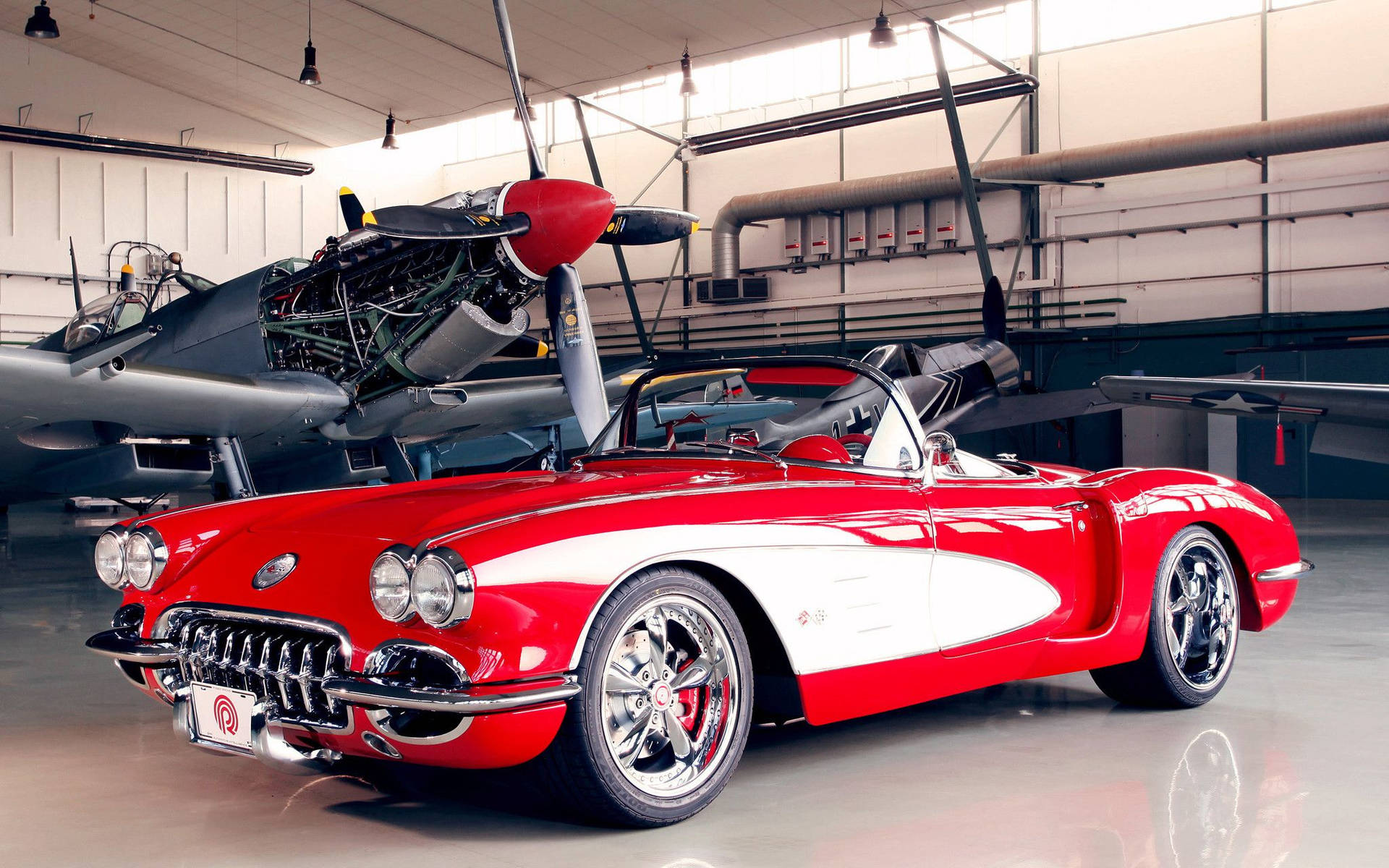 機庫內復古飛機旁邊的紅白經典Corvette敞篷車。 — 老車 壁紙