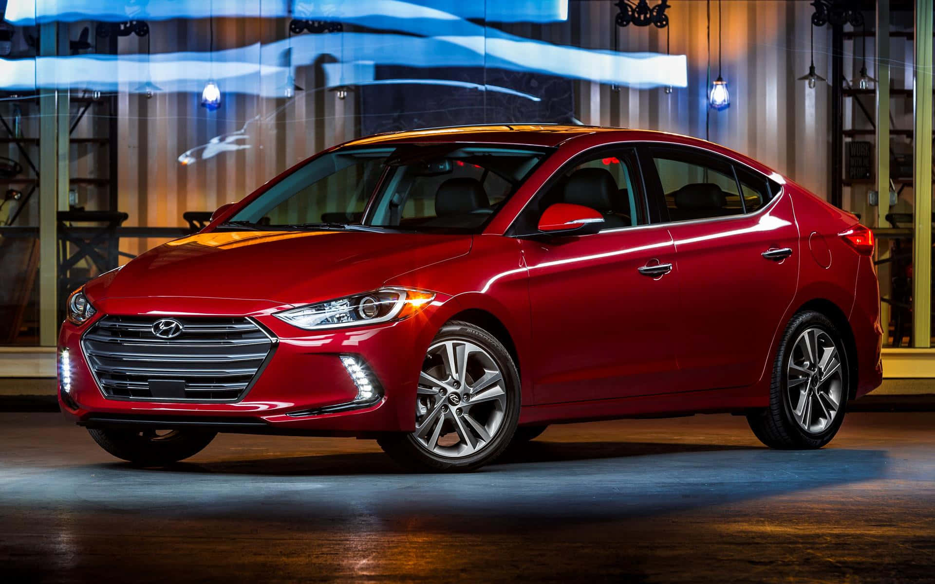 Hyundai Elantra 桌布 壁紙 — 一輛光澤的紅色現代伊蘭特轎車在戲劇性的工作室燈光下展示，帶有藍色條紋和溫暖的環境光暈。
