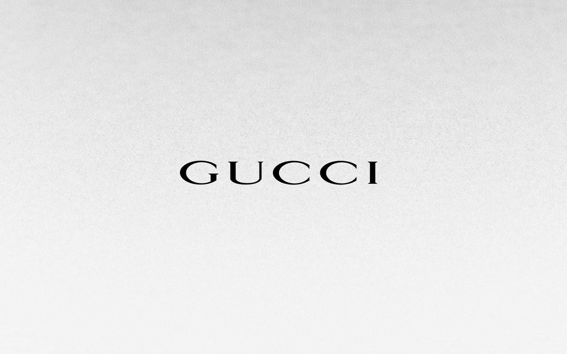 Gucci 桌布 壁紙 — Gucci 標誌以優雅的黑色襯線字體居中放置在帶紋理的淺灰色背景上。