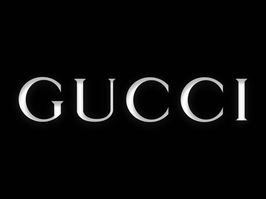 Gucci 桌布 壁紙 — Gucci 標誌以時尚的銀色字母在純黑色背景上發光，帶有柔和的光線亮點。