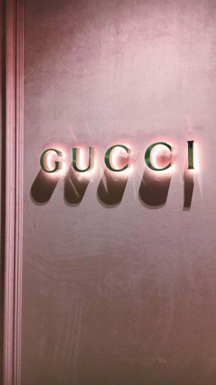 Boujee 桌布 壁紙 — Gucci 標誌字母在帶有紋理的粉紅色牆壁上散發溫暖光芒，投下柔和陰影。