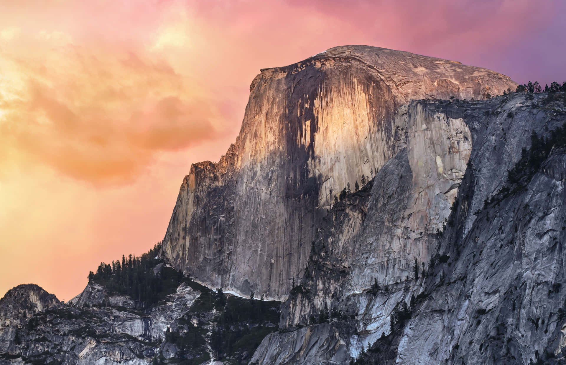 Half Dome 山沐浴在日落餘暉中，天空呈現粉紅和橙色。 — Macbook Pro 壁紙