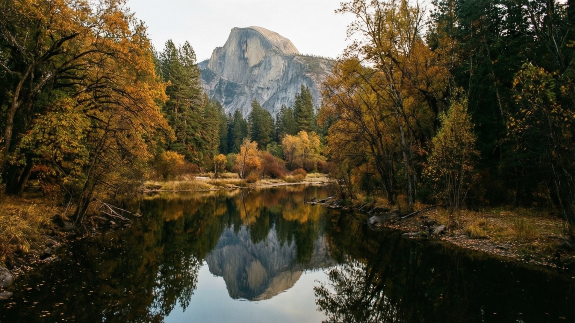 Half Dome Reflection 壁紙 — Half Dome 在平靜的河流後方雄偉地升起，河水映照出其花崗岩面，四周環繞著秋樹。