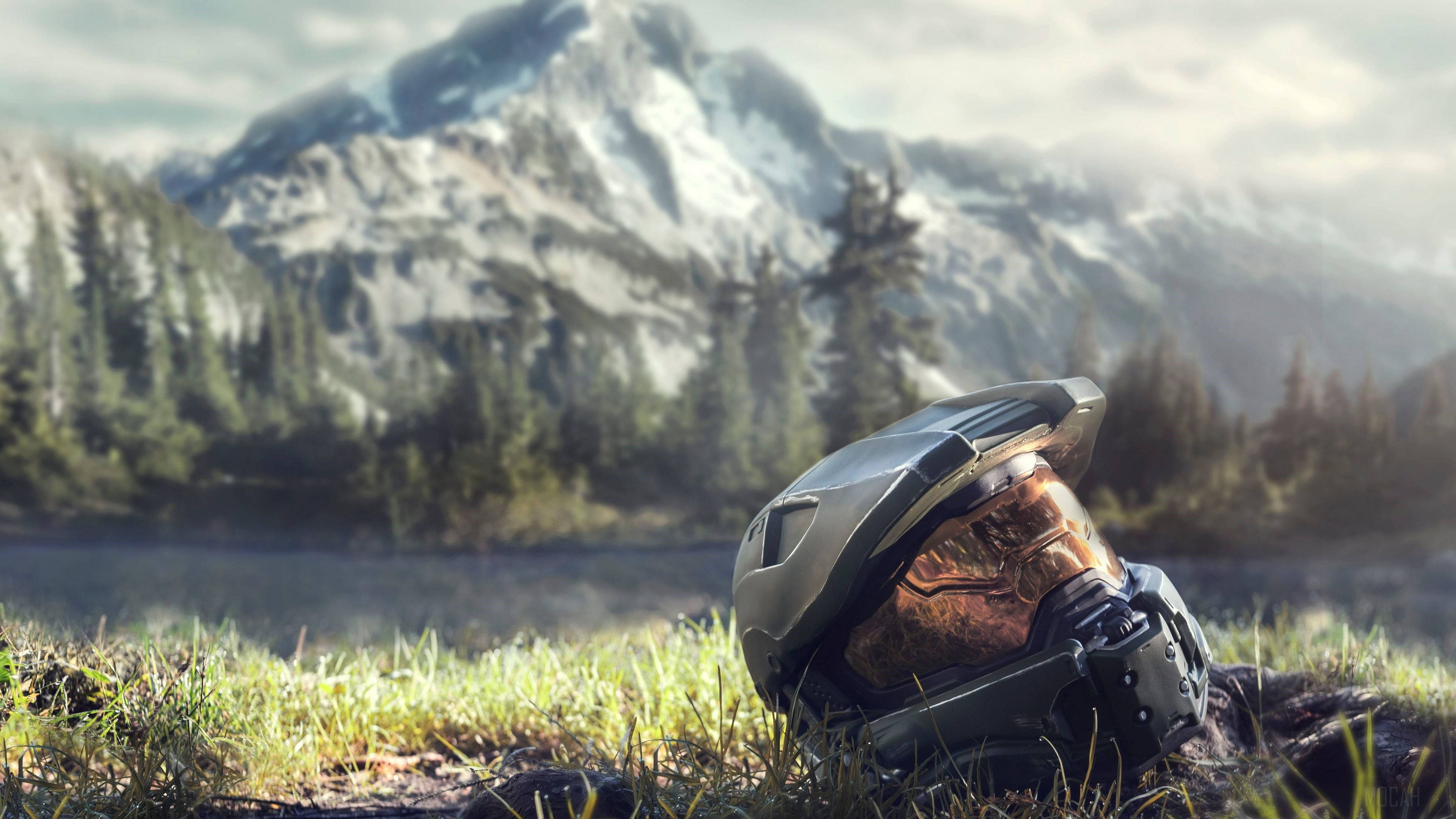 電玩遊戲 桌布 壁紙 — Halo Master Chief 頭盔放在草地上，前方是霧氣瀰漫的山湖和常綠樹。