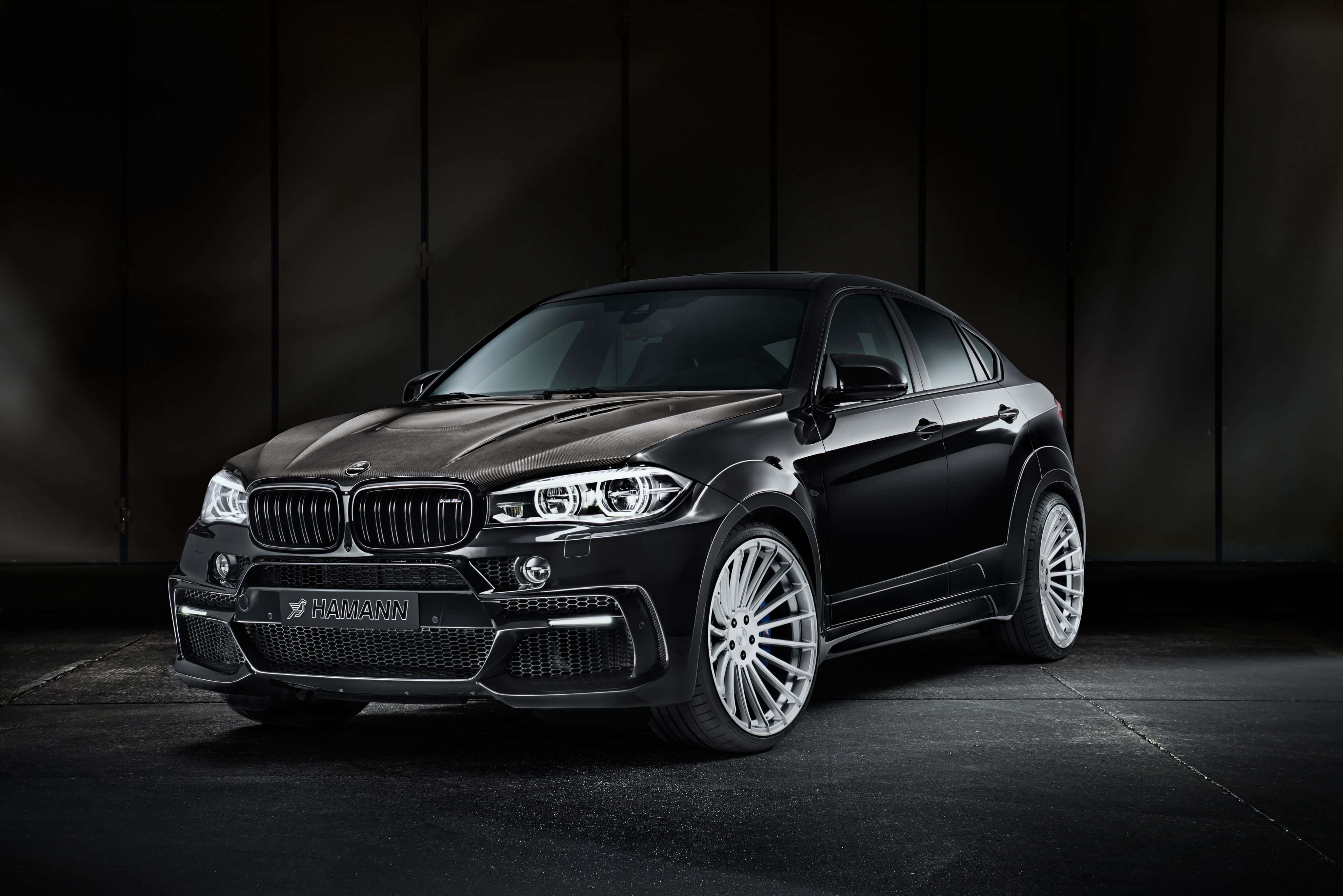 Bmw X6 桌布 壁紙 — 一輛由Hamann改裝的黑色BMW X6 M，在戲劇性的攝影棚燈光下，以深色紋理牆壁為背景，帥氣地佇立。