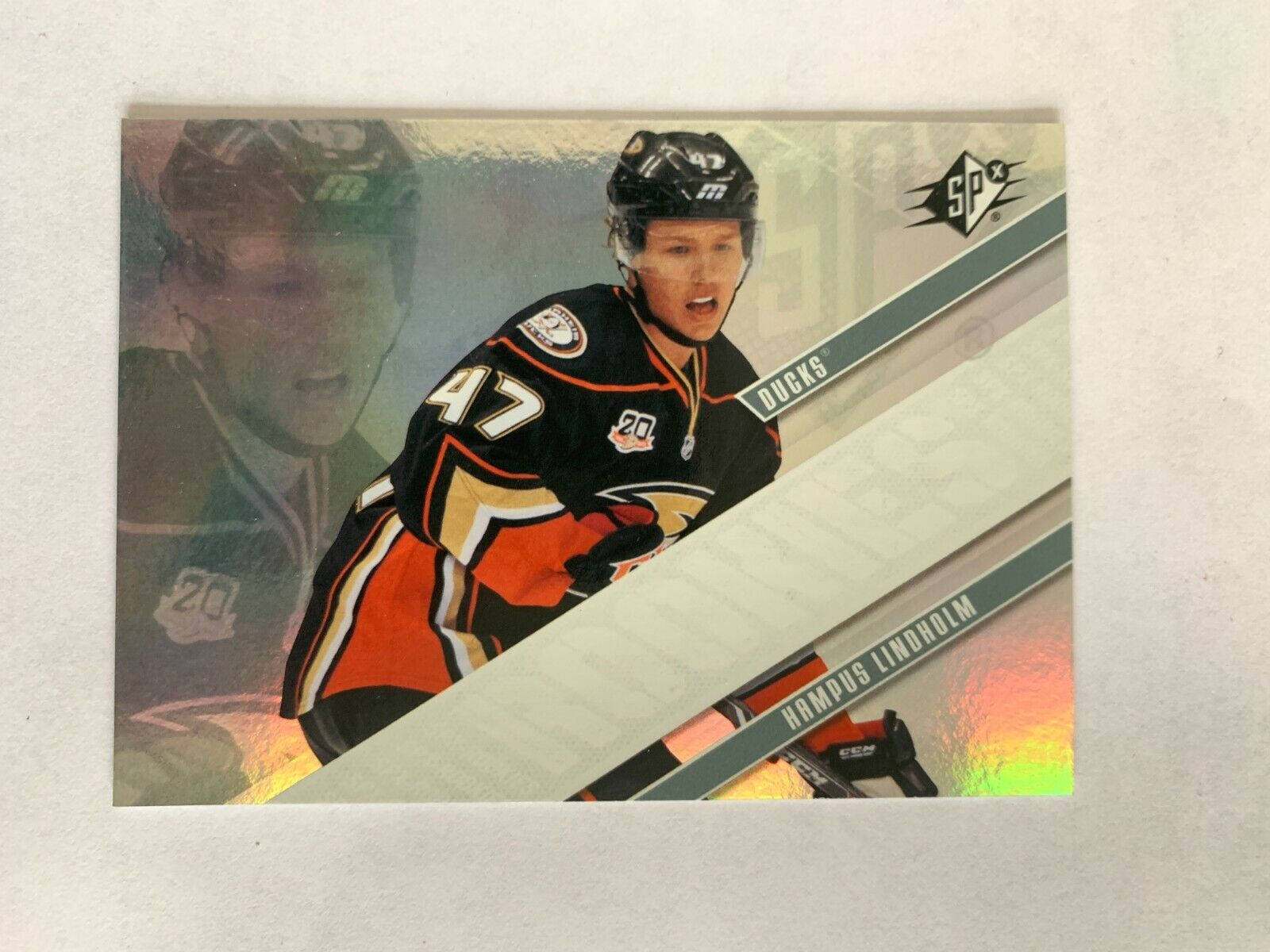 hockey 桌布 壁紙 — Hampus Lindholm 身穿 Anaheim Ducks 球衣，在一張帶有反光箔片裝飾的全息曲棍球交易卡上捕捉到動作中的瞬間。
