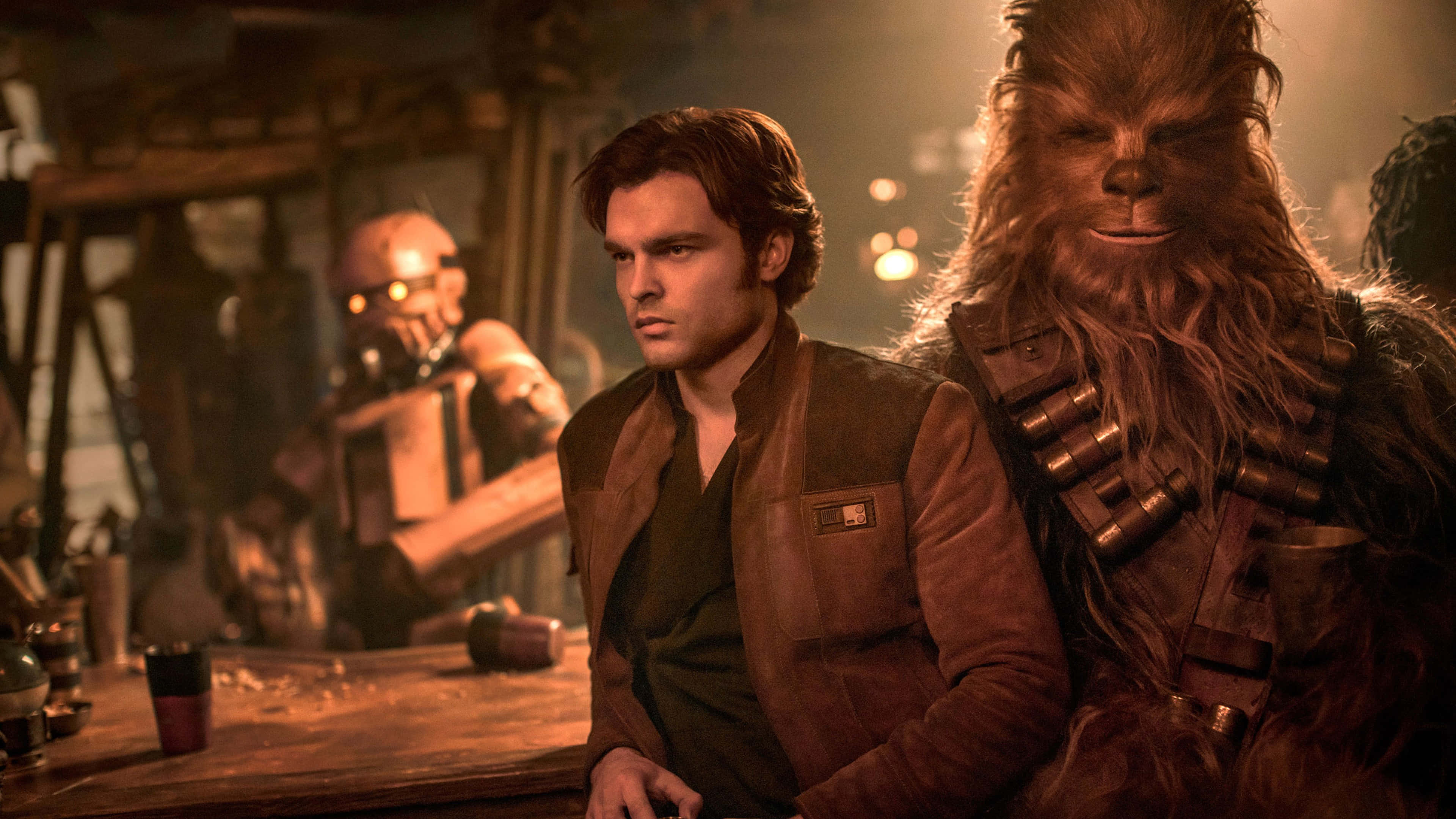 Solo A Star Wars Story 桌布 壁紙 — Han Solo 和 Chewbacca 坐在燈光昏暗的酒吧，溫暖的琥珀色燈光，背景有一個機器人。
