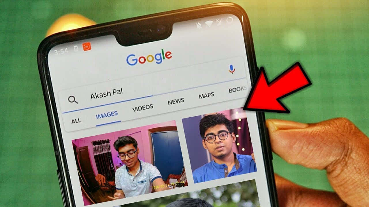 手拿著手機顯示Google搜尋Akash Pal，紅色箭頭指向他的圖像。 — Google 壁紙