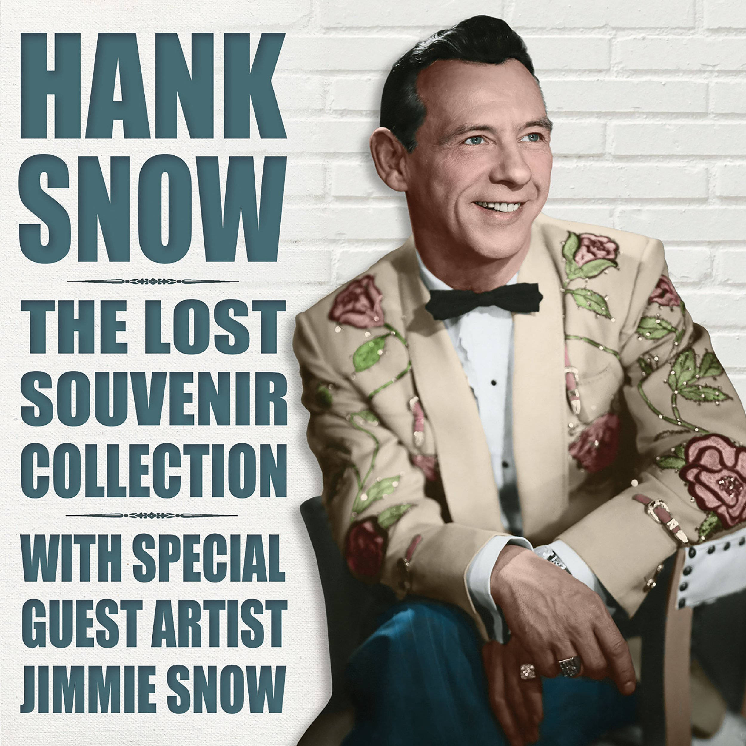 音樂 桌布 壁紙 — Hank Snow 穿著玫瑰刺繡西裝，在白色磚牆前微笑，帶有復古文字疊加。