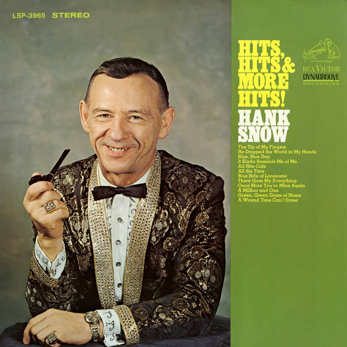 音樂 桌布 壁紙 — Hank Snow 穿著閃亮的黑色和金色西裝，手持煙斗，在柔和的灰色背景前溫暖微笑，旁邊是充滿活力的綠色專輯封套，列出他的熱門歌曲。