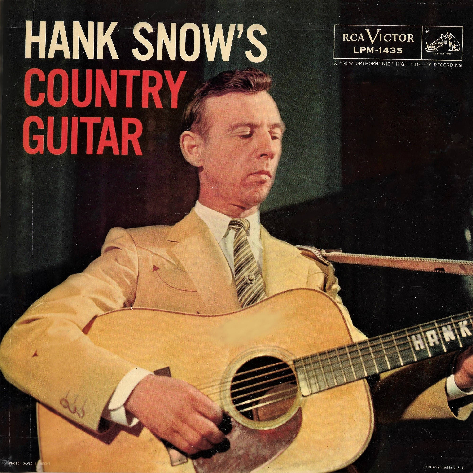 音樂 桌布 壁紙 — Hank Snow 身穿棕褐色西裝，在復古 RCA Victor 專輯封面上彈奏原聲吉他，搭配大膽的紅色和奶油色字體。