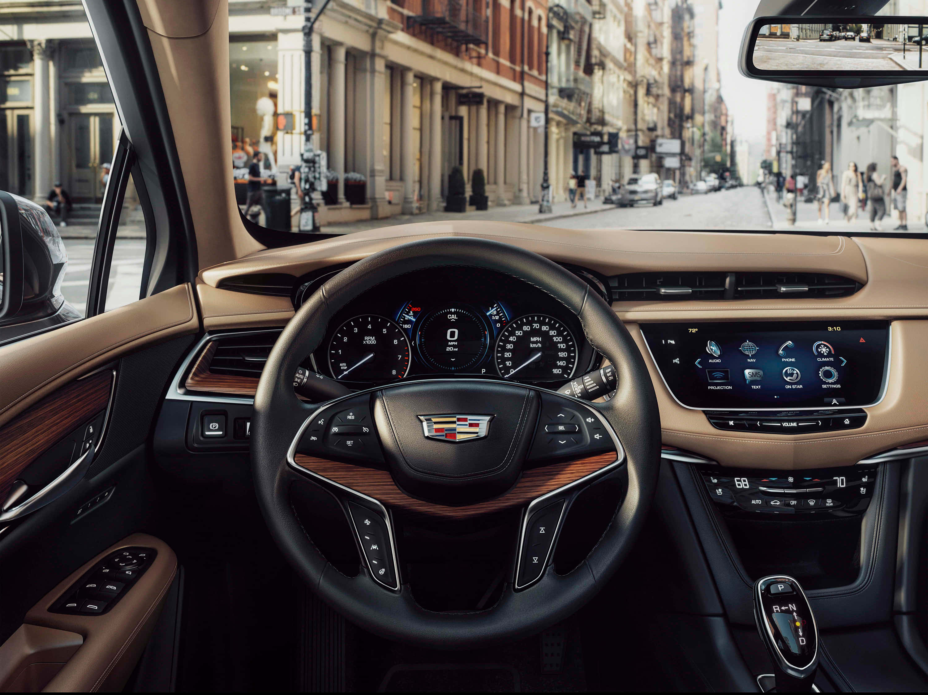 Cadillac Xt5 桌布 壁紙 — 豪華車內裝，配備棕褐色皮革和木質飾邊，透過擋風玻璃俯瞰繁華的城市街道。
