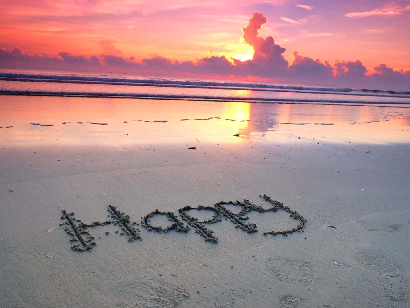 1440x1080 桌布 壁紙 — 「happy」這個字寫在沙灘的沙上，日落時分有充滿活力的粉橙色天空和海浪。