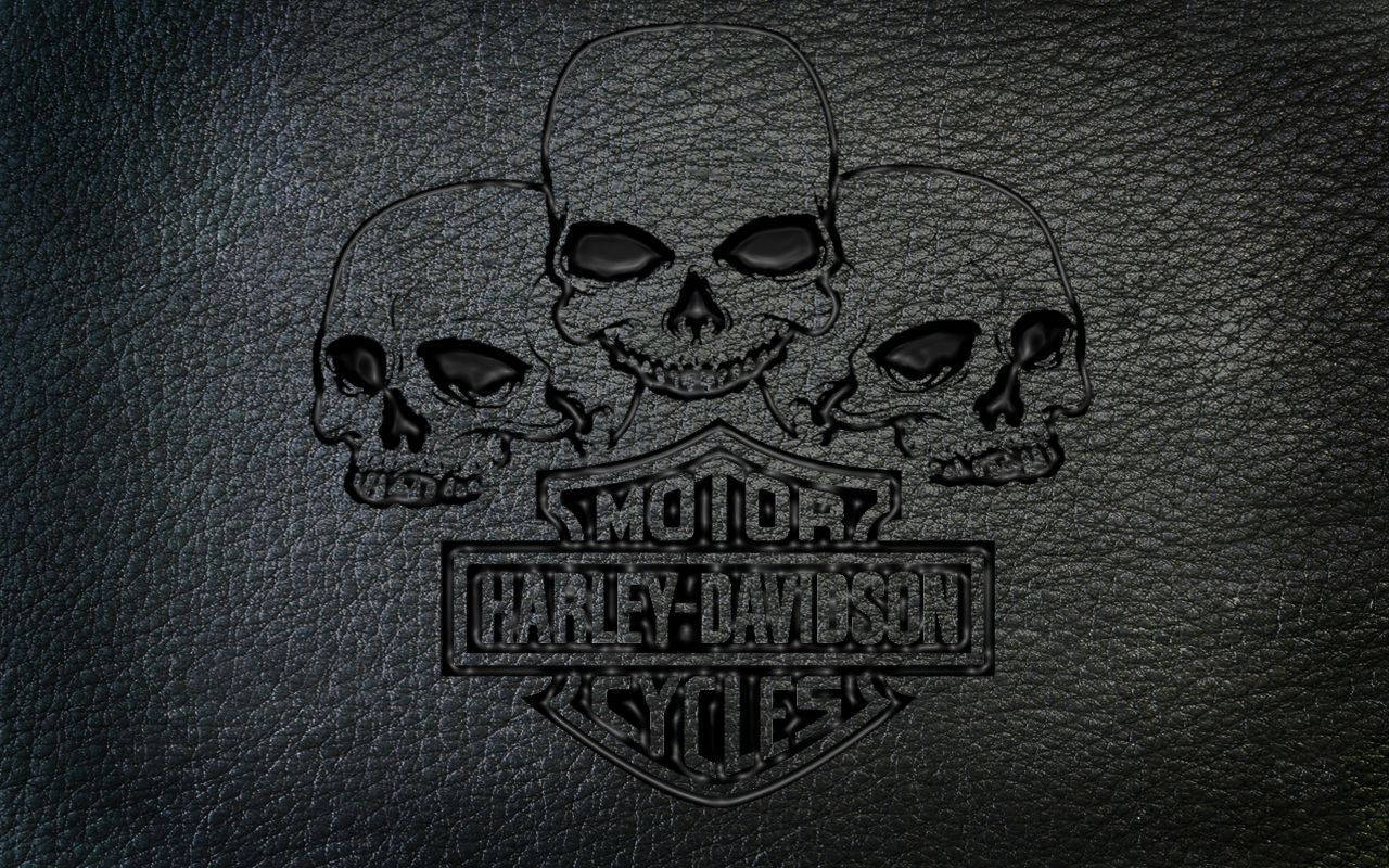 Harley 桌布 壁紙 — Harley-Davidson 標誌，三個骷髏頭壓印在深色紋理皮革背景上。