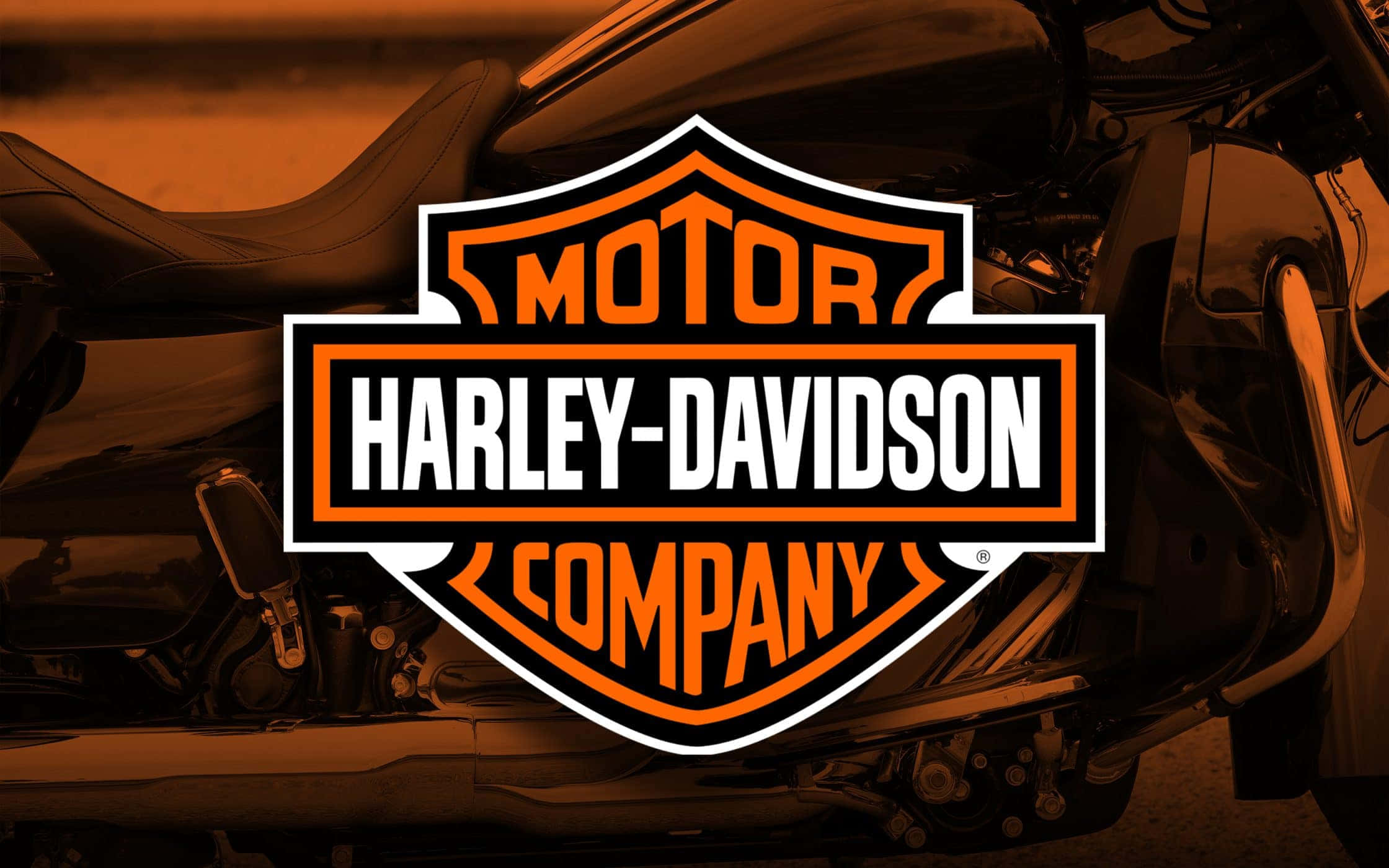哈雷戴維森 桌布 壁紙 — Harley-Davidson 標誌顯眼地展示在摩托車上，帶有溫暖的橙色和黑色色調。