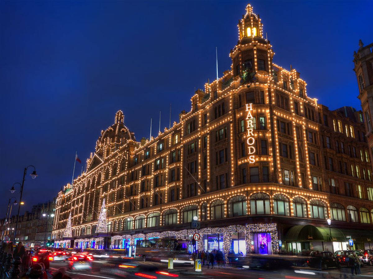 City Lights 桌布 壁紙 — Harrods 百貨公司在深藍色夜空下閃耀著金色燈光，模糊的汽車燈光掠過。