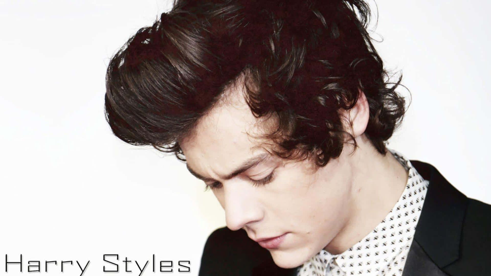Harry Styles Black And White 桌布 壁紙 — Harry Styles 向下凝視，一頭凌亂的黑髮，背景是純白色，身穿黑色西裝外套和圖案襯衫。