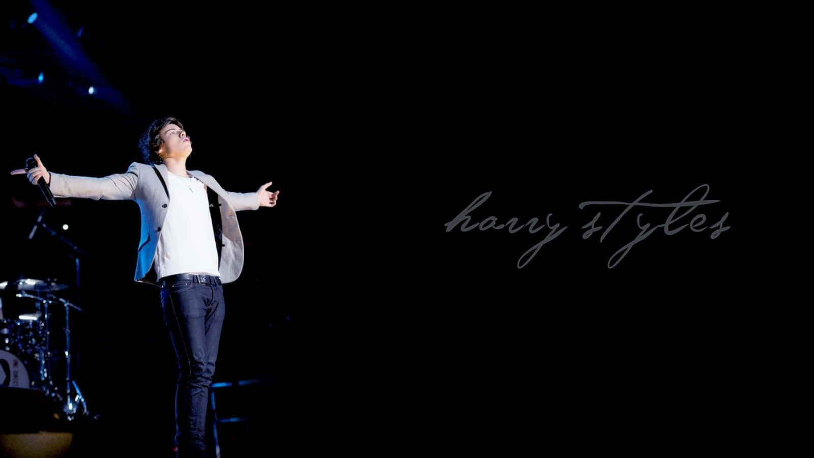 哈利·史泰爾斯 桌布 壁紙 — Harry Styles 在黑暗舞台上於聚光燈下張開雙臂表演，旁邊可見草書名字。