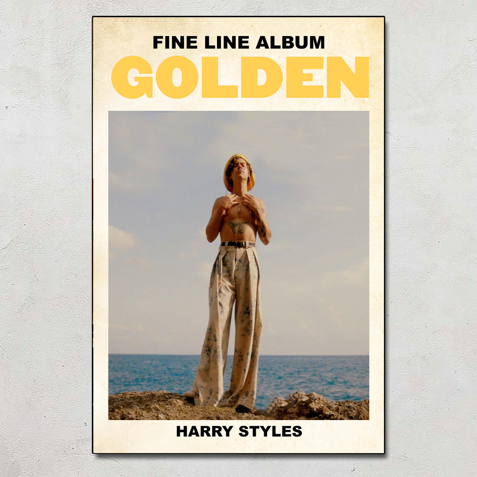 哈利·史泰爾斯 桌布 壁紙 — Harry Styles 赤裸上身站在岩石懸崖上，俯瞰多雲天空下的海洋，並以粗體黃色文字顯示專輯名稱 'Golden'。