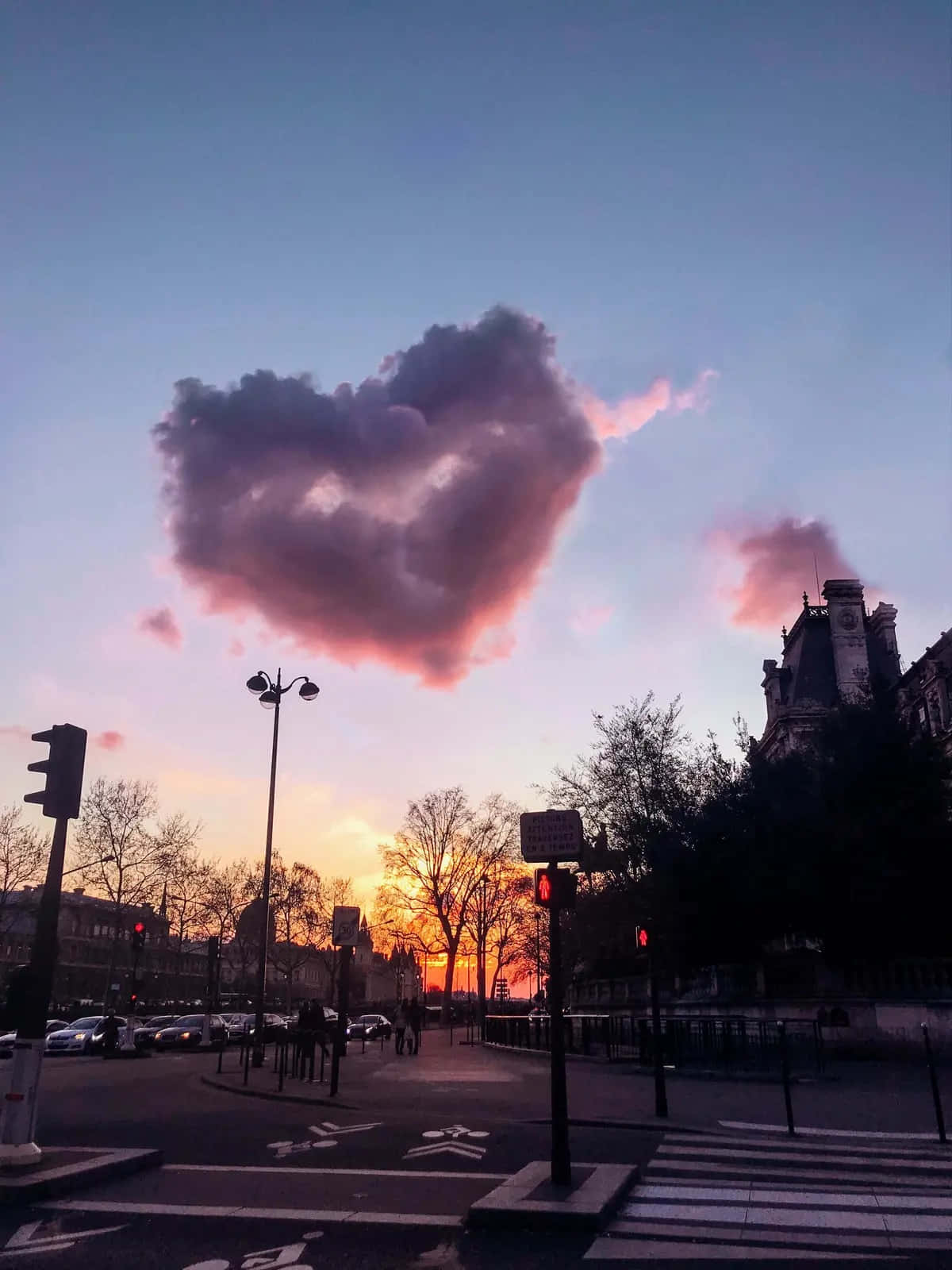 I Love God 桌布 壁紙 — 一顆心形雲在巴黎街道上方的日落時分發出粉紅和紫色光芒，襯托出樹木和交通燈的剪影。