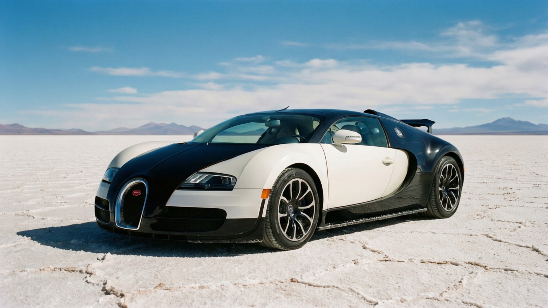 Salt Flat Veyron 壁紙 — 一輛黑白相間的布加迪威龍獨自停在龜裂的鹽灘上，背景是明亮的藍天和遠山。