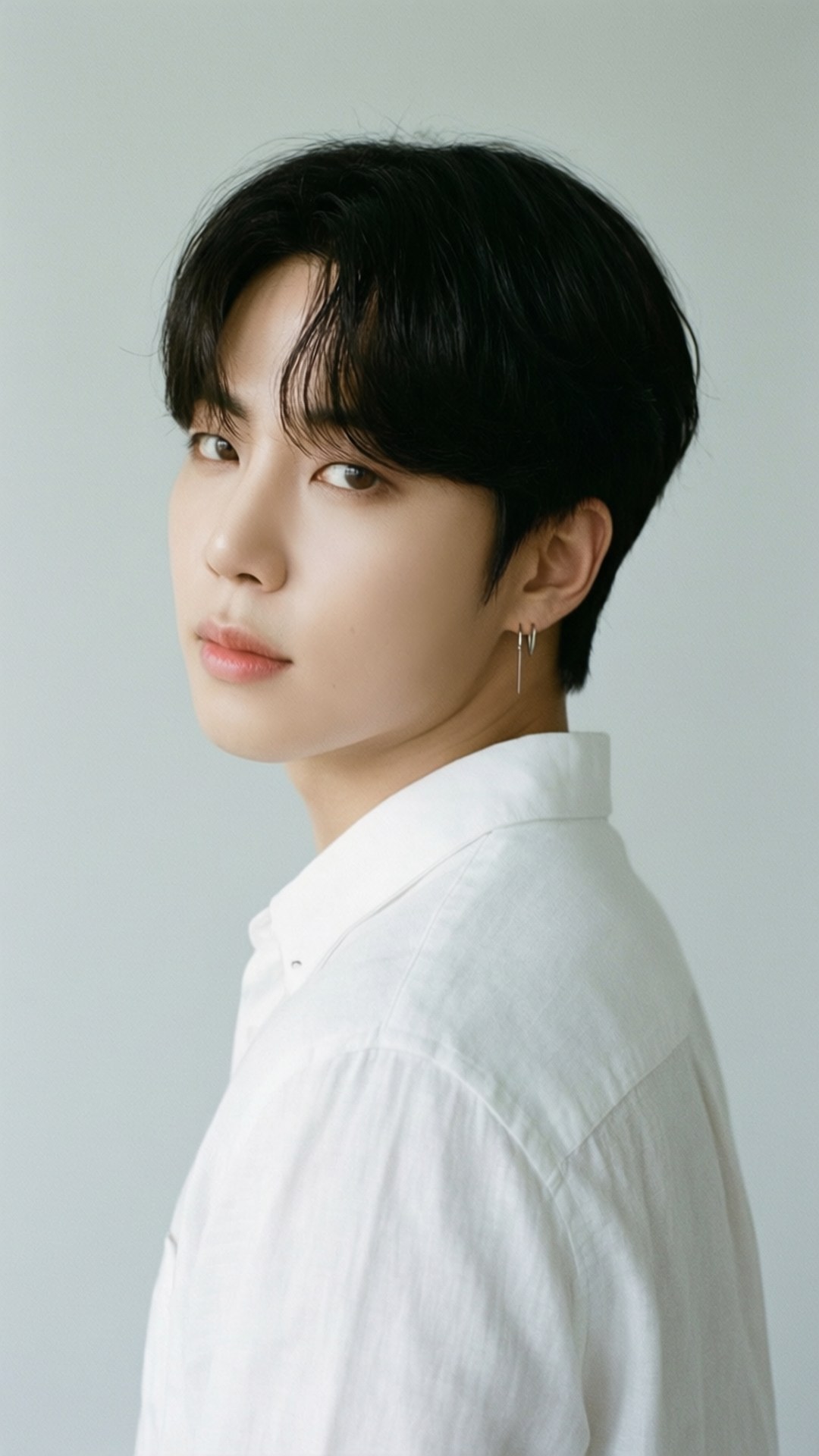 Minimalist White Shirt 壁紙 — 一位黑髮、身穿白襯衫的年輕男子，在純淺灰色背景前微微轉頭。