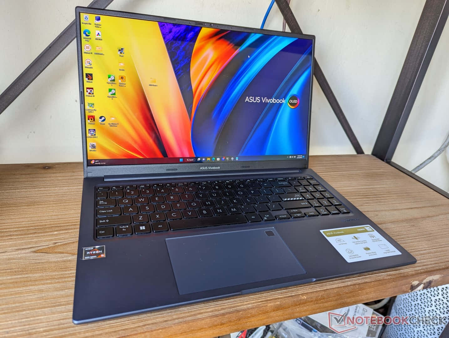木桌上的黑色ASUS Vivobook筆記型電腦，彩色螢幕 — Asus 壁紙