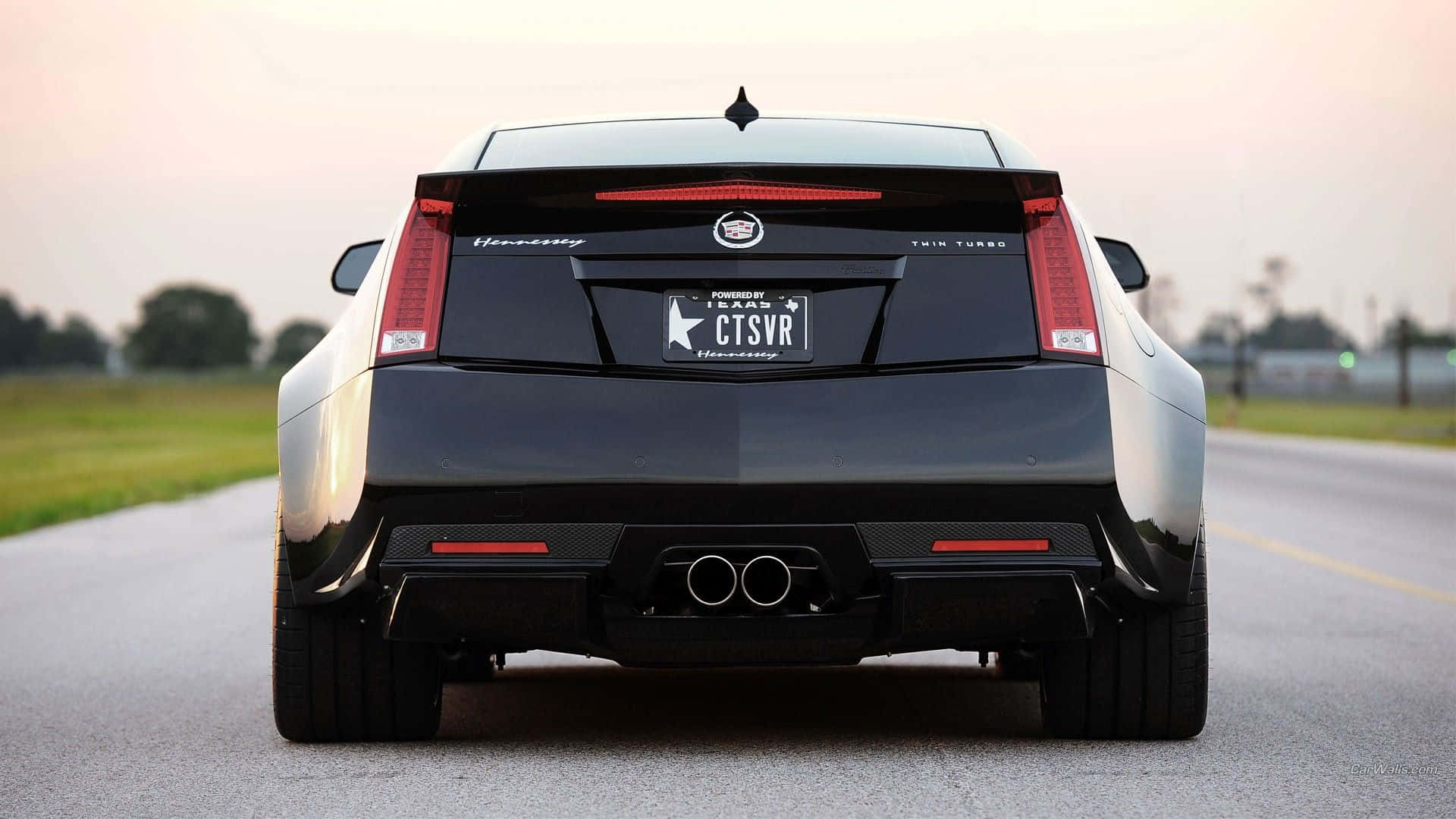 Cadillac Cts 桌布 壁紙 — 黑色Cadillac CTS-VR在黃昏時分在鄉村道路上疾馳，尾燈發光的後視圖。