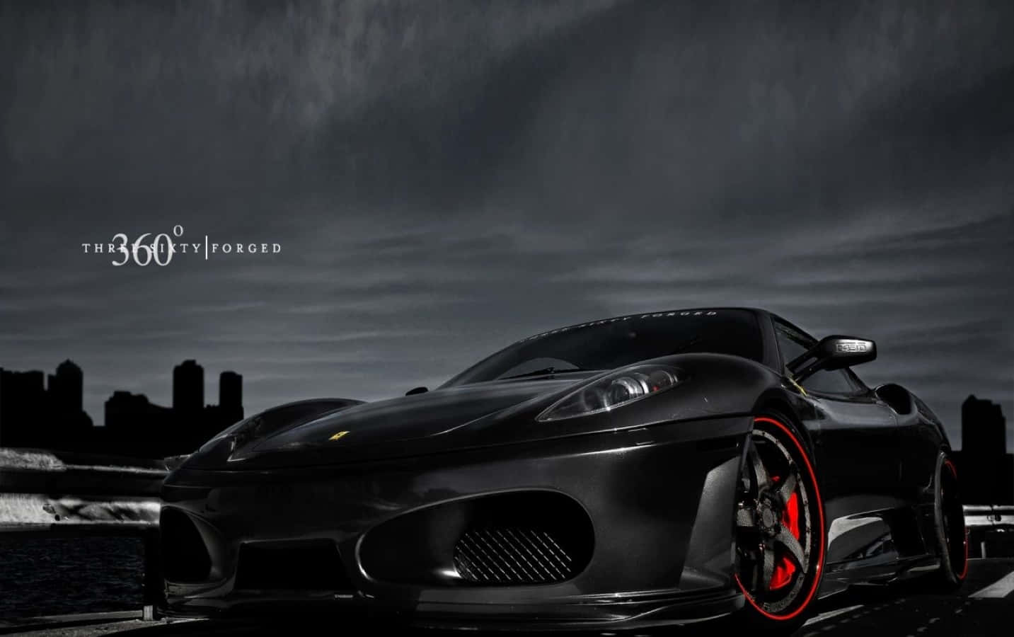 Ferrari 360 Modena 桌布 壁紙 — 一輛時尚的黑色法拉利跑車，帶有紅色煞車卡鉗，停在潮濕的道路上，背景是暴風雨的天空和城市天際線。