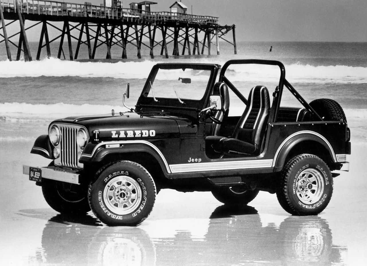 Jeep Cj 桌布 壁紙 — 一輛黑色Jeep Wrangler Laredo停在沙灘的濕沙上，背景有木製碼頭。