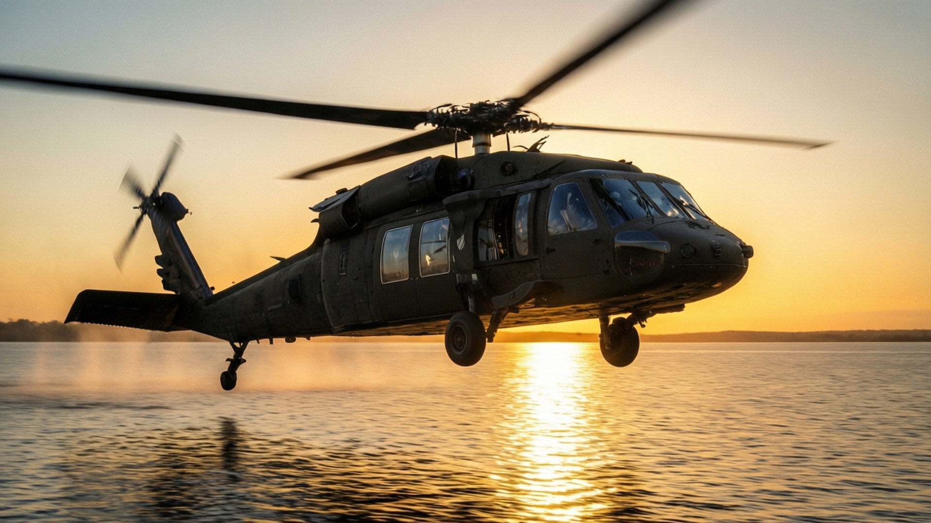 Helo Over Water 壁紙 — 一架黑色軍用直升機低空盤旋在平靜的水面上，夕陽在其後方落下，投射出金色的倒影。