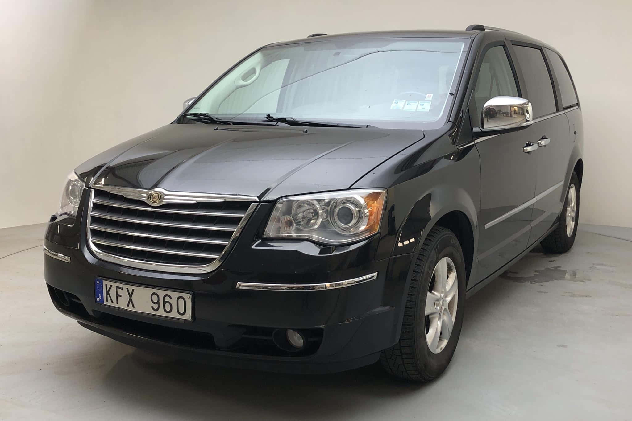 Chrysler Voyager 桌布 壁紙 — 一輛時尚的黑色克萊斯勒小型貨車，帶有鍍鉻裝飾和歐洲車牌，停在簡約的攝影棚空間中。